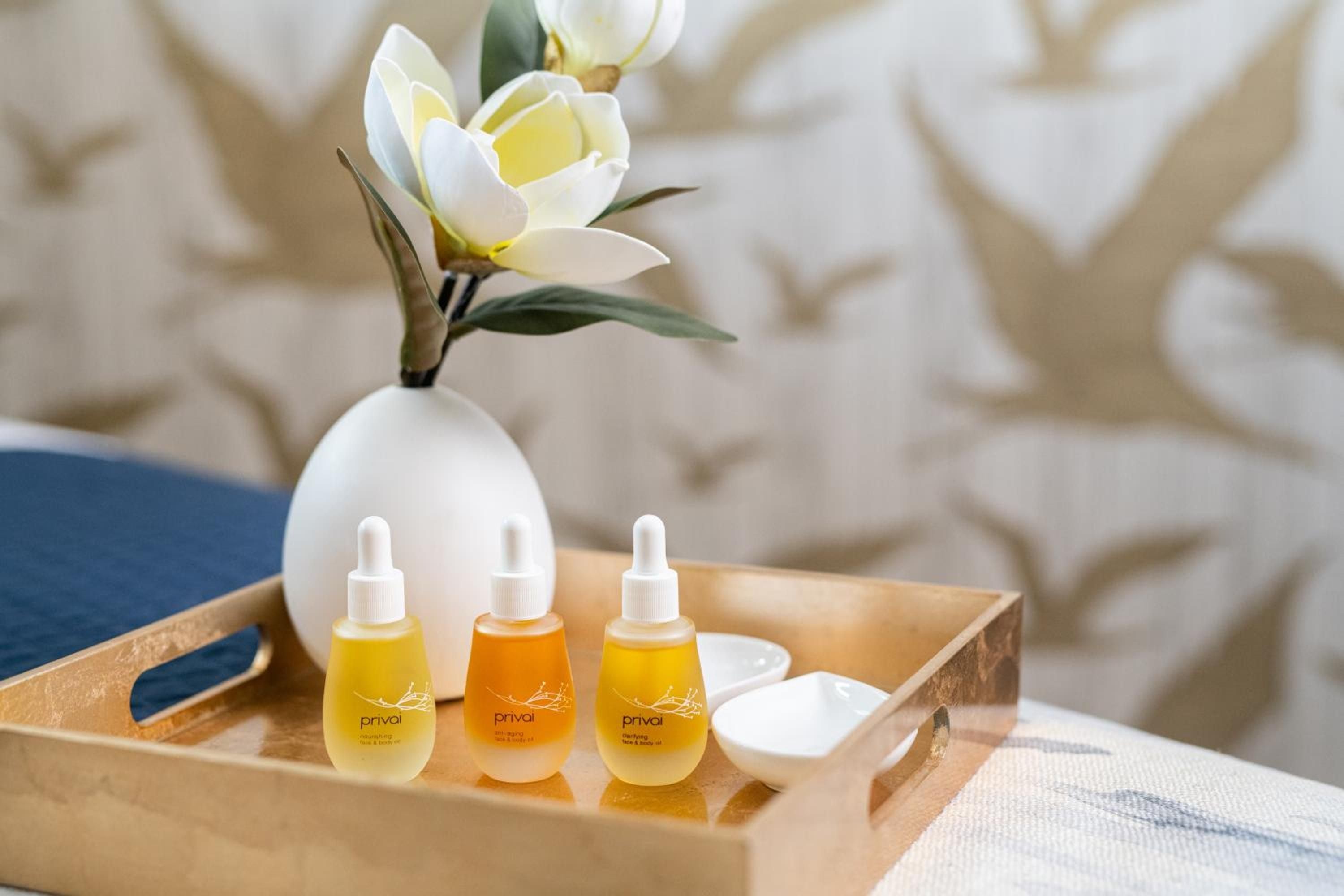 Golden serums catch afternoon light on polished wood, while fresh magnolia blooms create an intimate sanctuary for Priva's signature facial treatments.