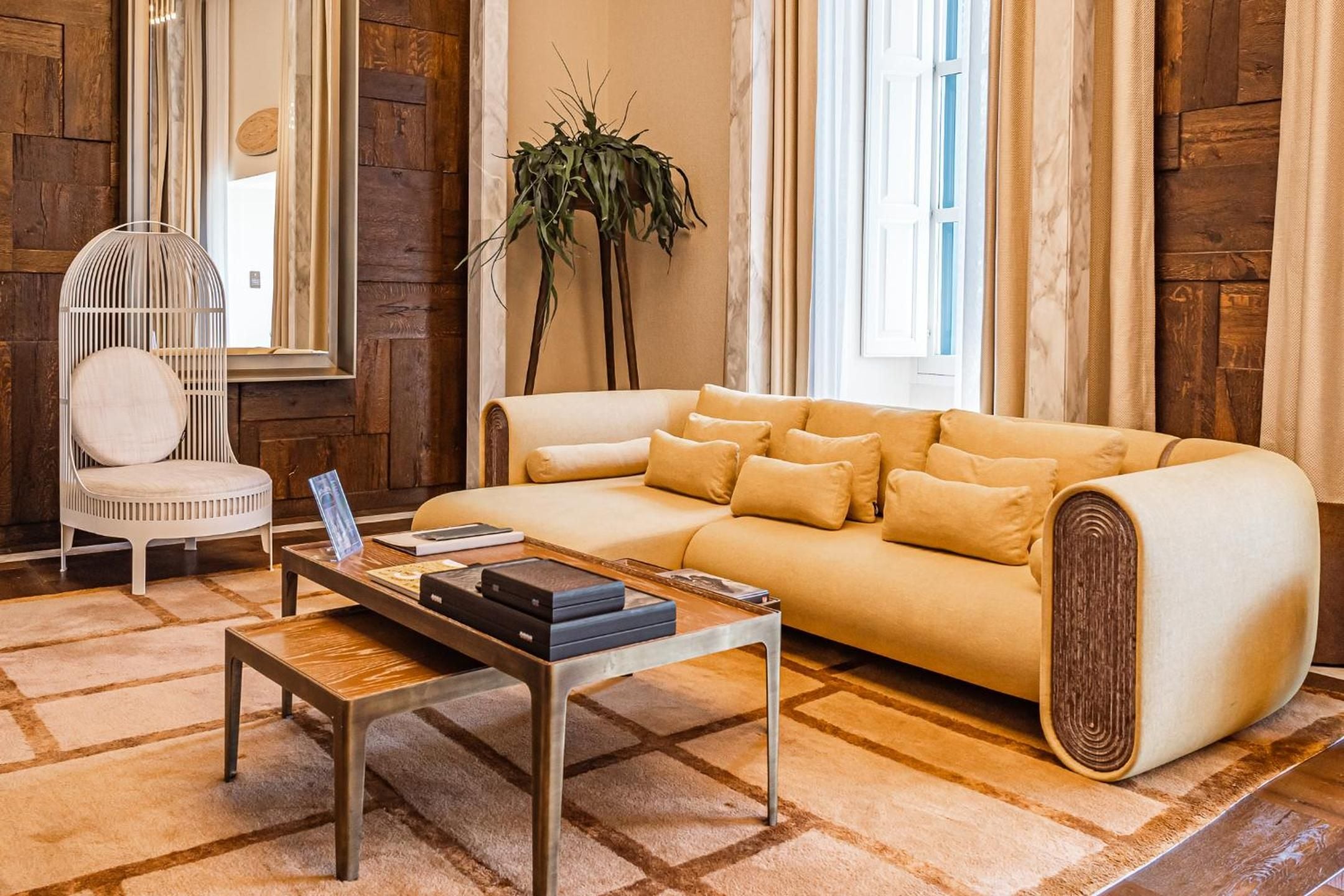 Sculptural furniture and warm wood paneling create an artful seating area where contemporary design meets organic textures, bathed in golden afternoon light.