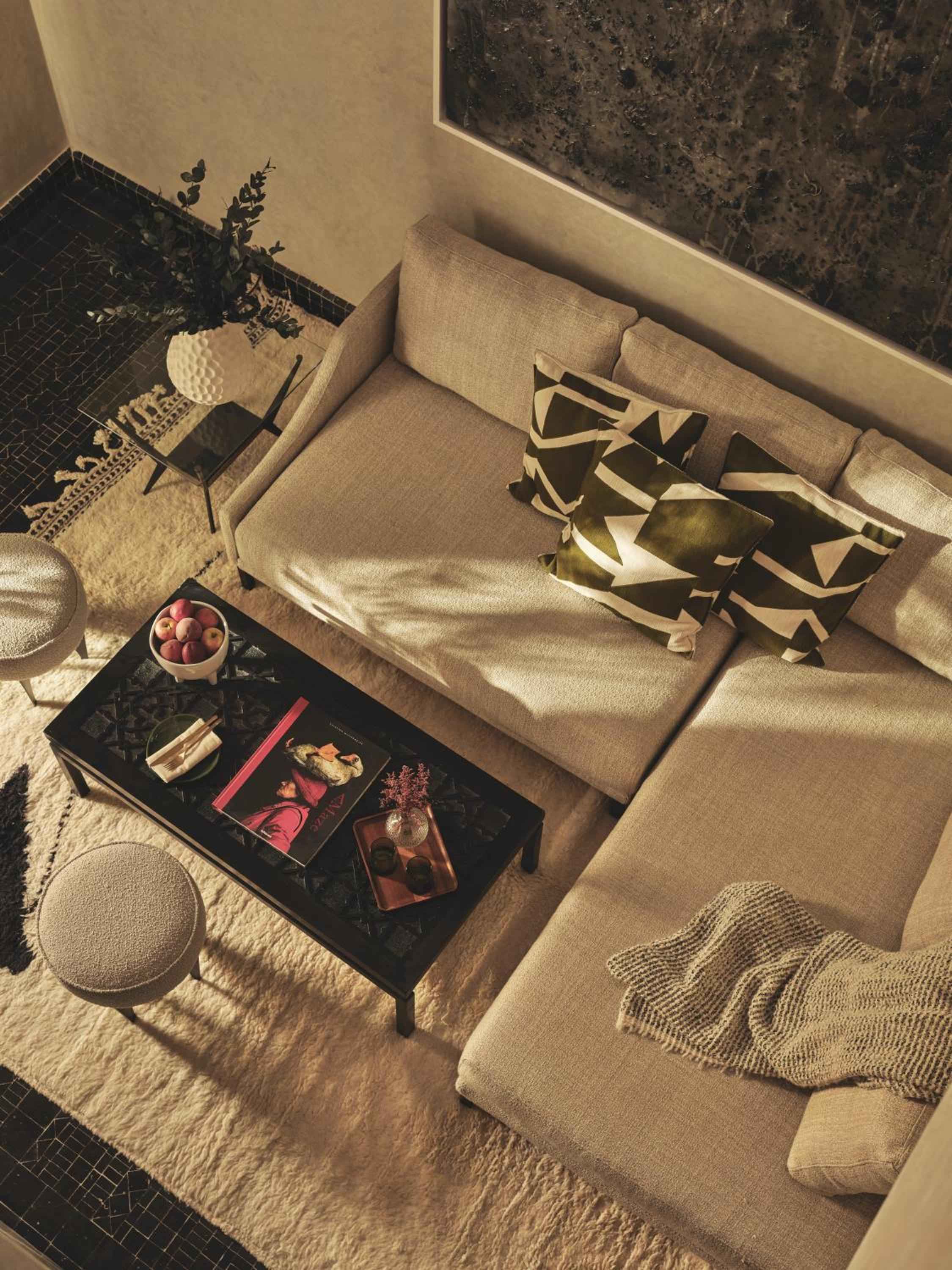 Geometric throw pillows and warm afternoon light transform a neutral sectional into an inviting oasis, where traditional Moroccan patterns meet contemporary comfort.