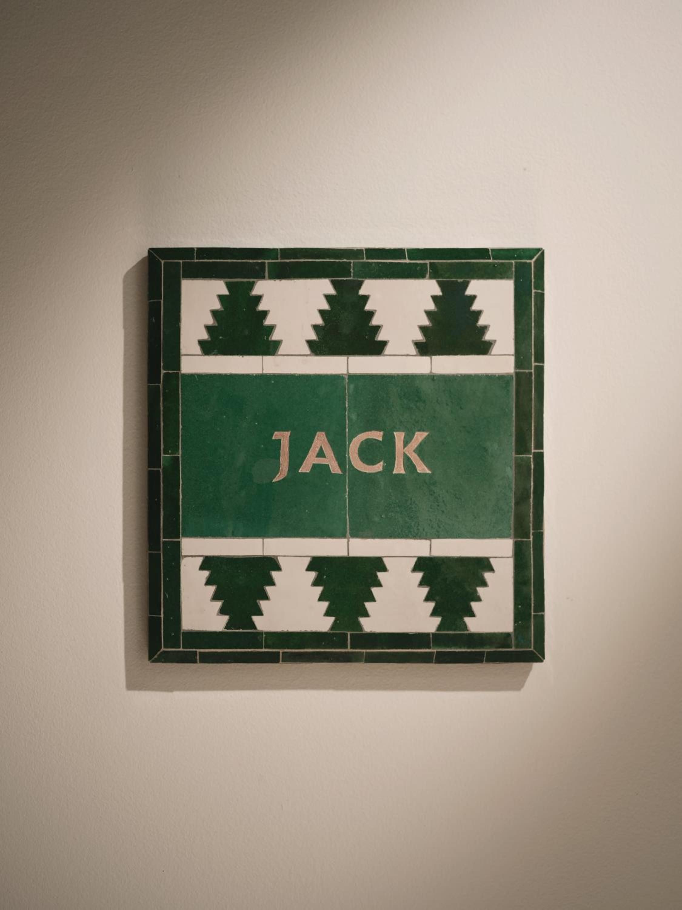 Hand-painted ceramic tiles spell out 'JACK' in emerald green, showcasing the artisanal craftsmanship that defines this boutique riad's intimate, personalized aesthetic.