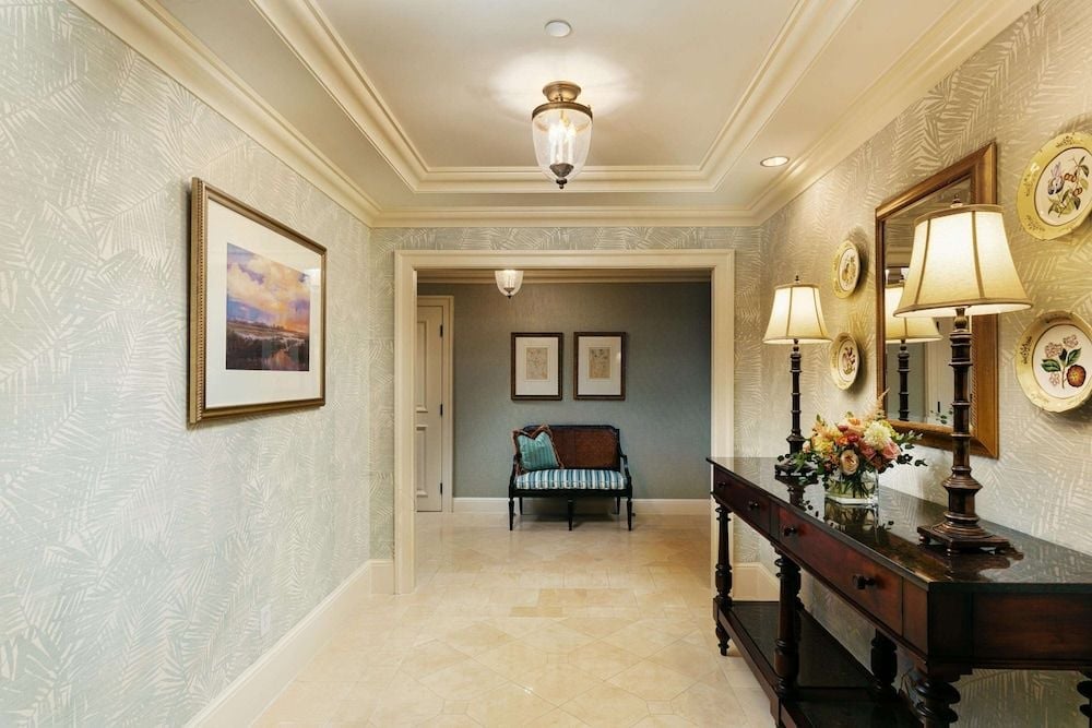 Elegant hallways showcase refined coastal luxury with grasscloth wallpaper, gleaming marble floors, and carefully curated artwork that whispers Southern sophistication.