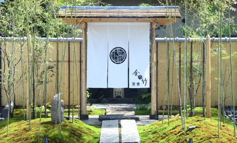 Bamboo fencing and moss-covered gardens frame the traditional noren curtain entrance, where ancient Japanese hospitality meets contemporary zen design in perfect harmony.