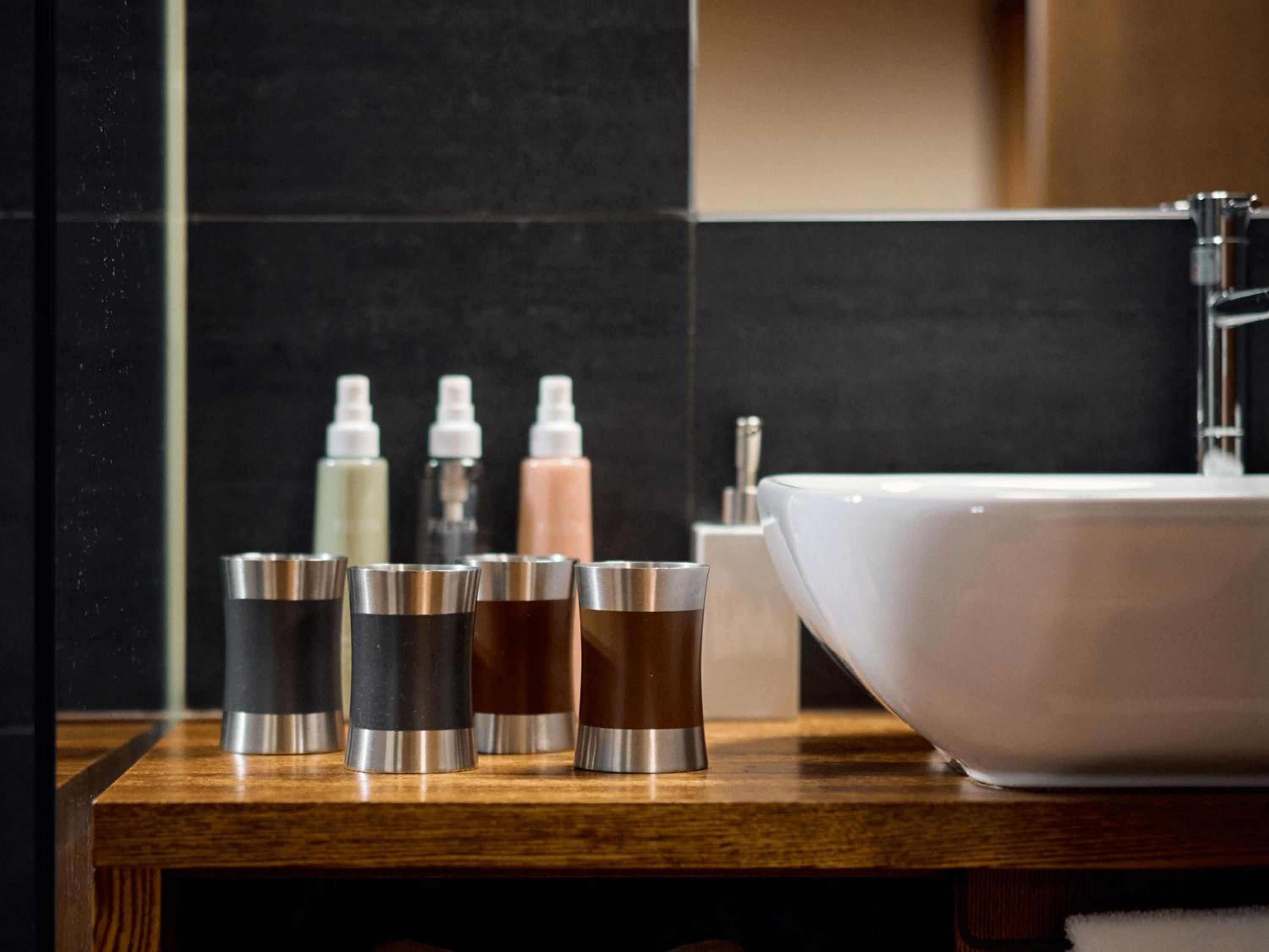 Sleek vessels with metallic trim and artisanal spray bottles line warm wood surfaces, creating a spa-like sanctuary where modern luxury meets Japanese minimalism.