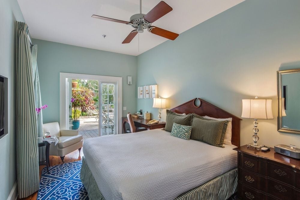 Seafoam walls and polished wood create a serene retreat, where morning light spills through French doors onto geometric blue rugs and crisp linens.