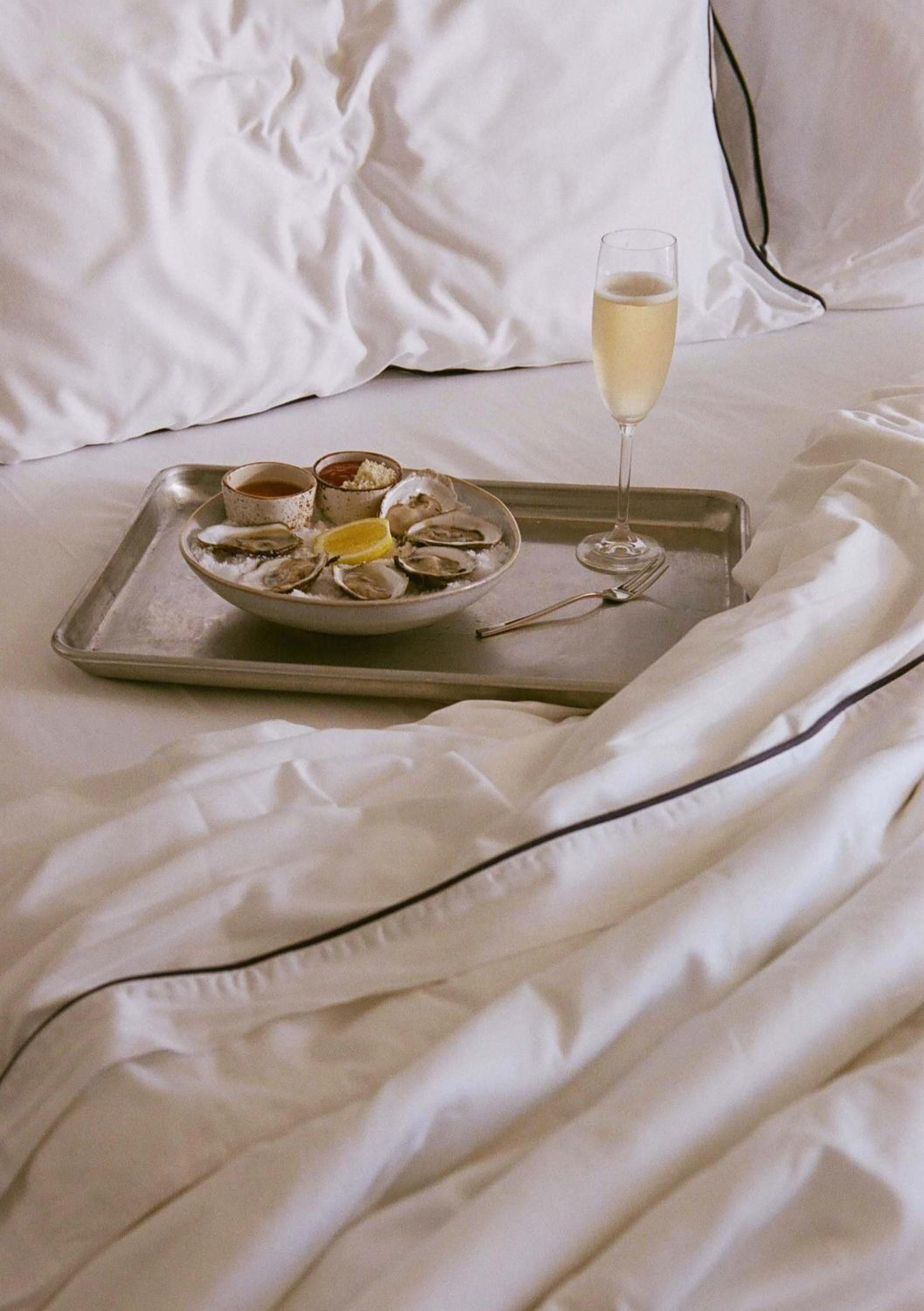 Crisp white linens frame a decadent oyster service and champagne—the kind of indulgent in-room dining that makes checking out feel impossible.