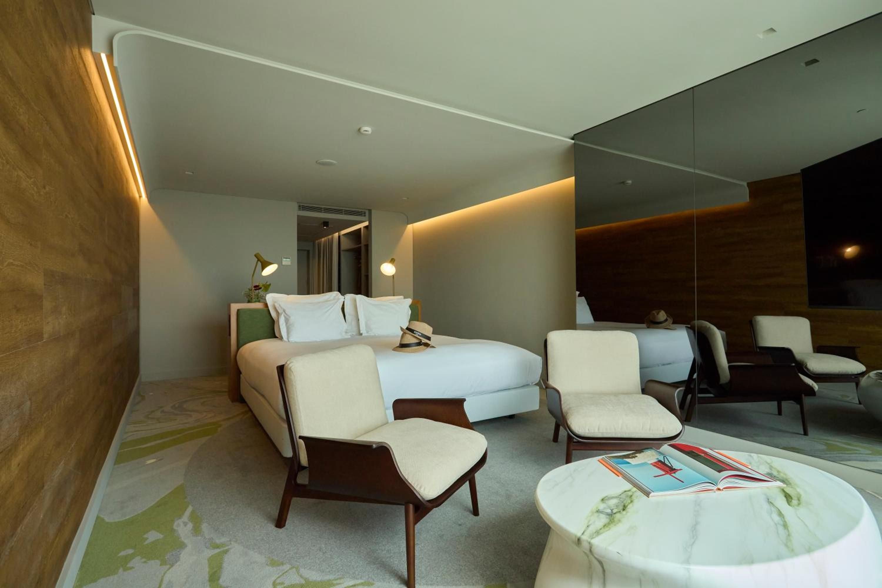 Warm wood textures and cool marble surfaces create serene contrast in this thoughtfully designed suite, where curved ceilings and hidden lighting embrace modern comfort.