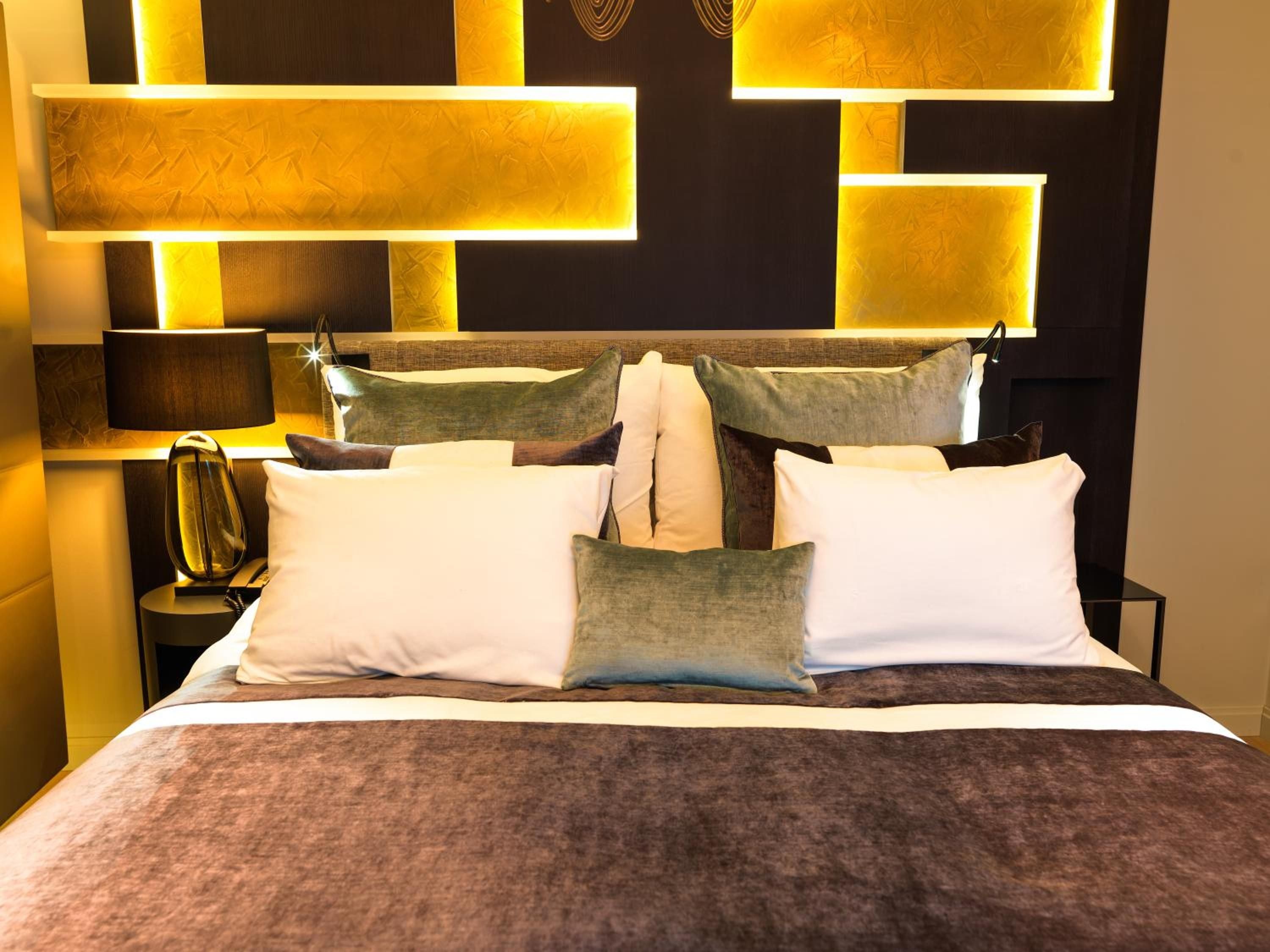 Warm amber lighting illuminates sculptural wall niches behind the bed, creating an intimate cocoon where rich textures and earth tones invite complete relaxation.