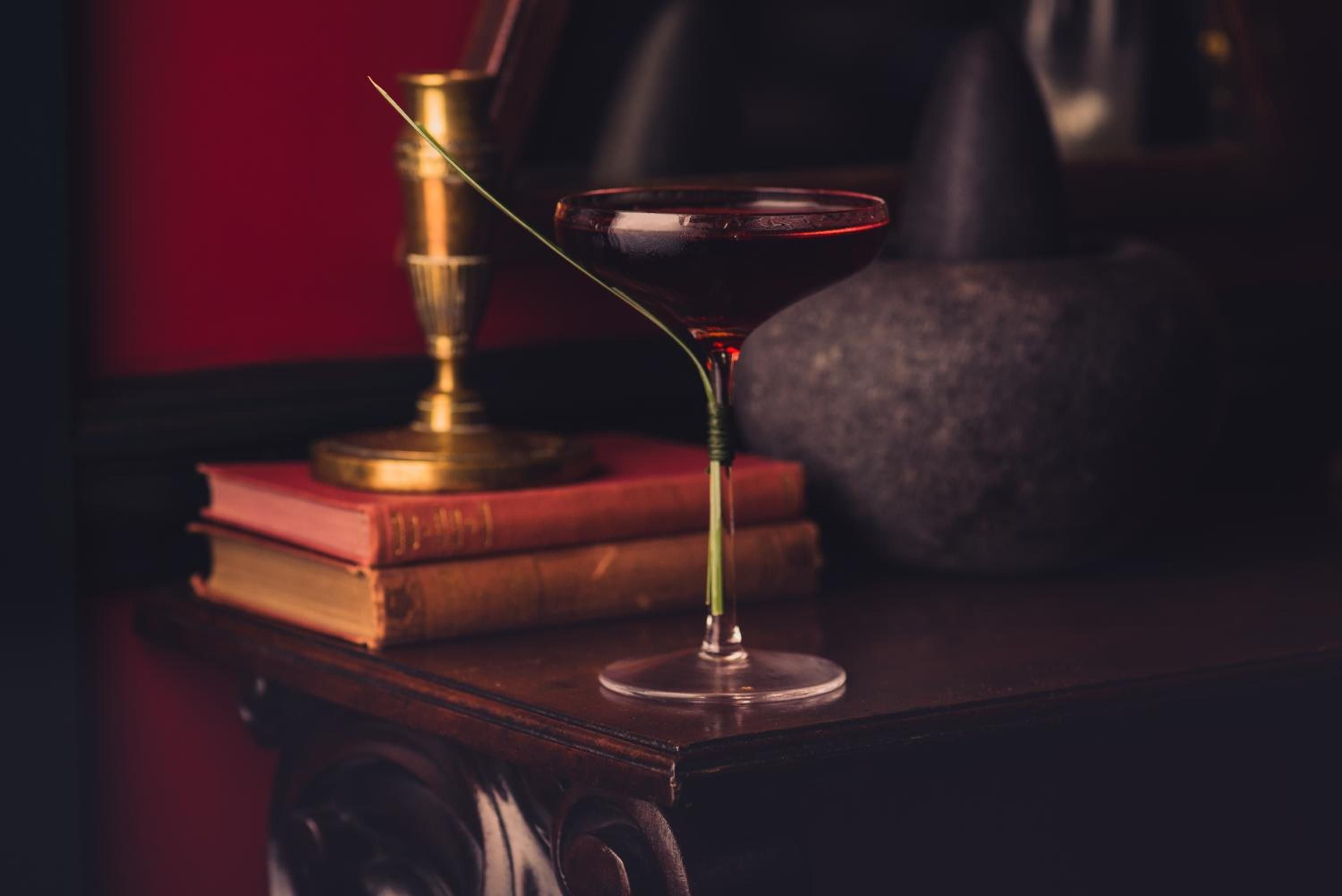 Candlelit cocktails and leather-bound volumes create an intimate literary salon atmosphere, where brass details gleam against mahogany and conversations unfold over perfectly crafted libations.