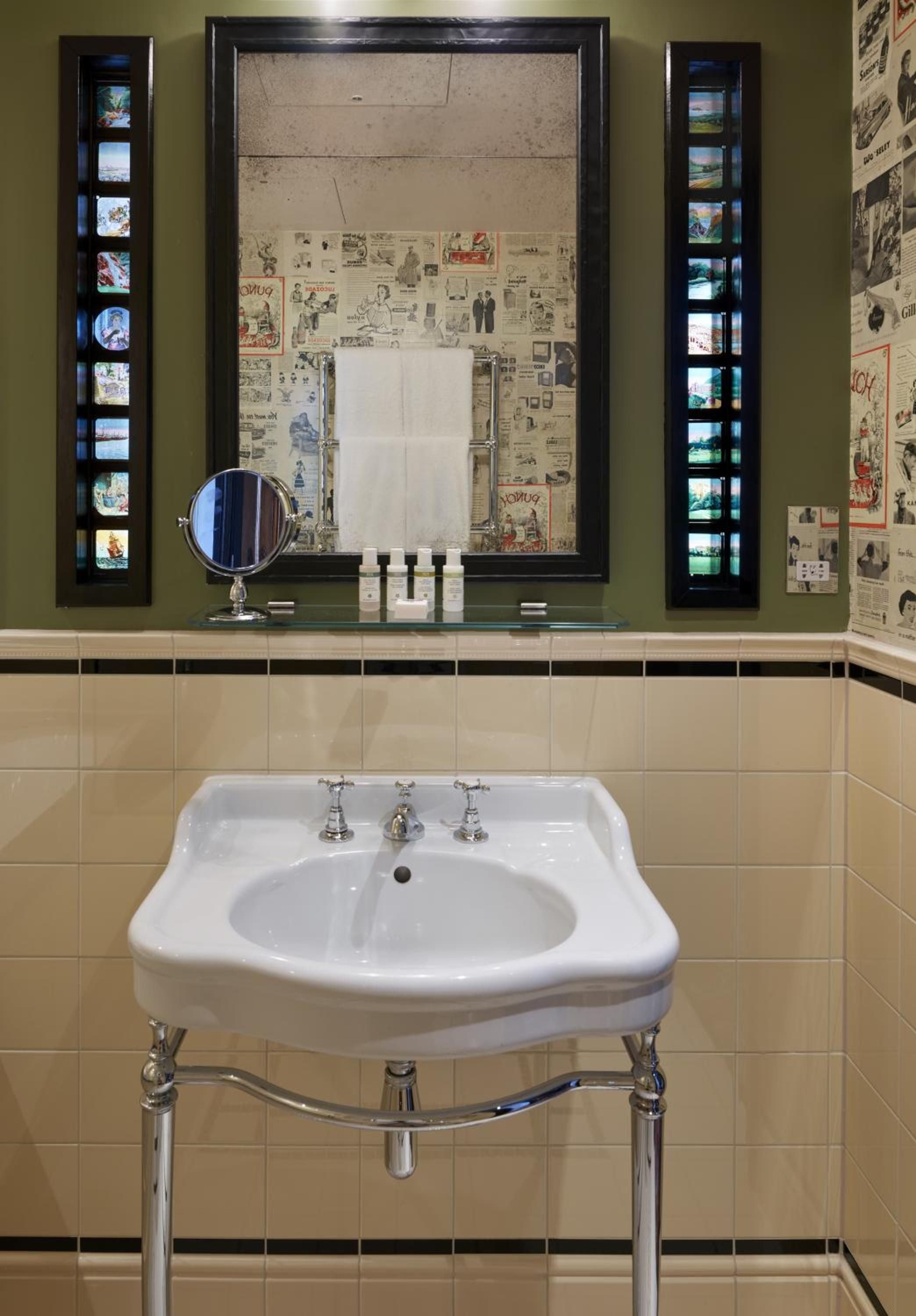 Vintage film strips frame the mirror above a classic console sink, where newspaper clippings and nostalgic collectibles create an intimate, curiosity-filled powder room.