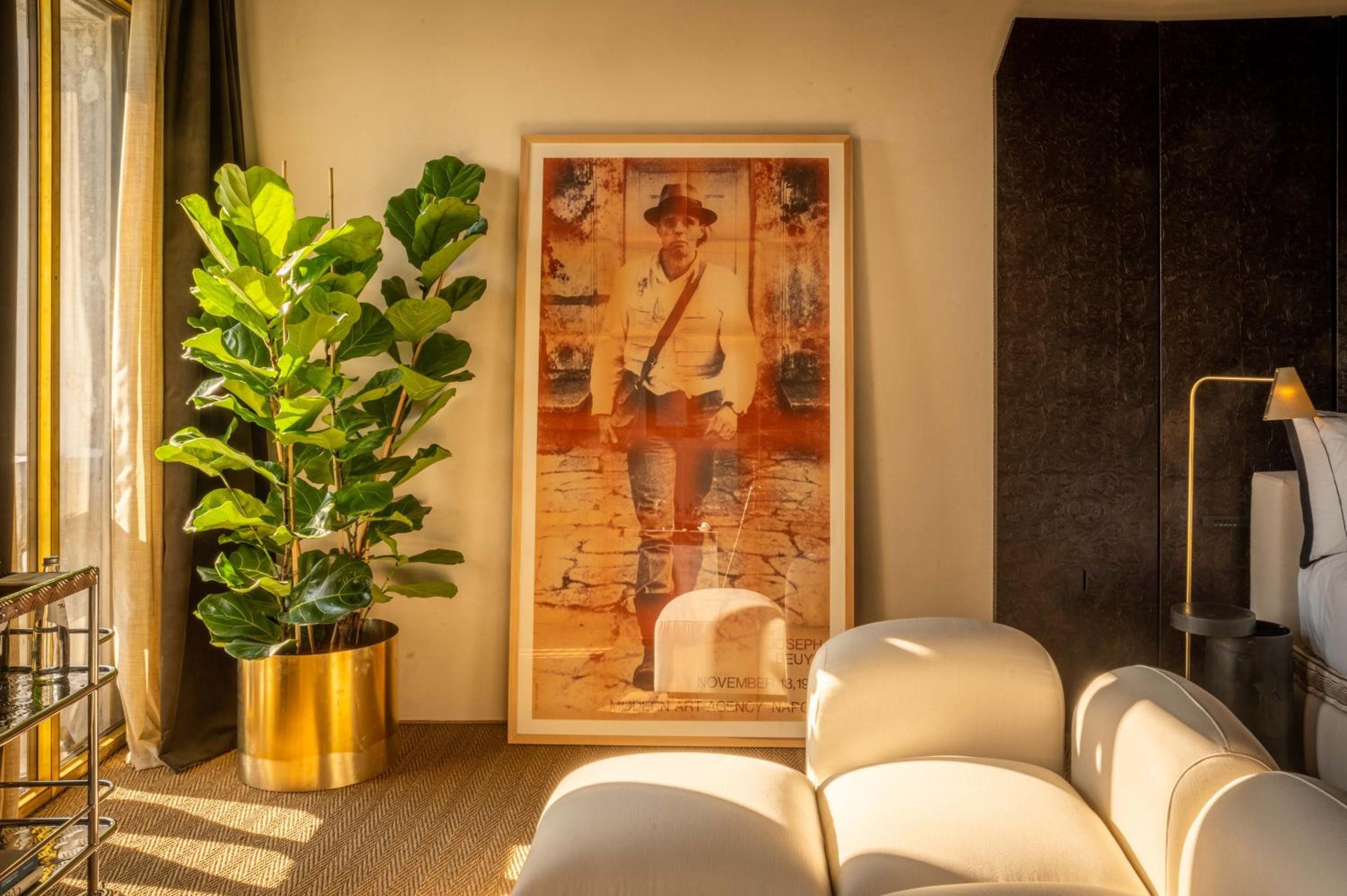 Warm afternoon light illuminates a thoughtfully curated corner where vintage photography meets contemporary comfort, brass accents catching golden hour rays through gauze curtains.