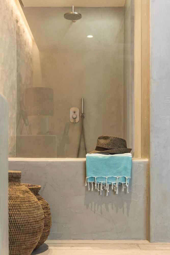 Natural stone and warm wood frame this serene shower sanctuary, where rainfall heads and handwoven baskets create an organic spa-like retreat.
