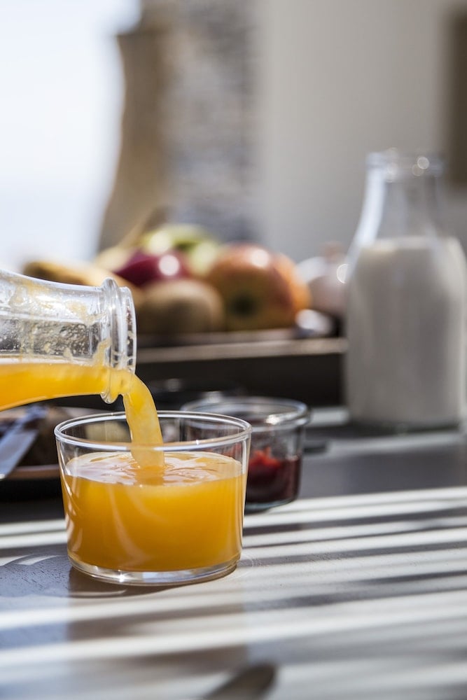 Golden orange juice streams into a glass as morning light filters across the breakfast spread, promising leisurely Mediterranean mornings ahead.