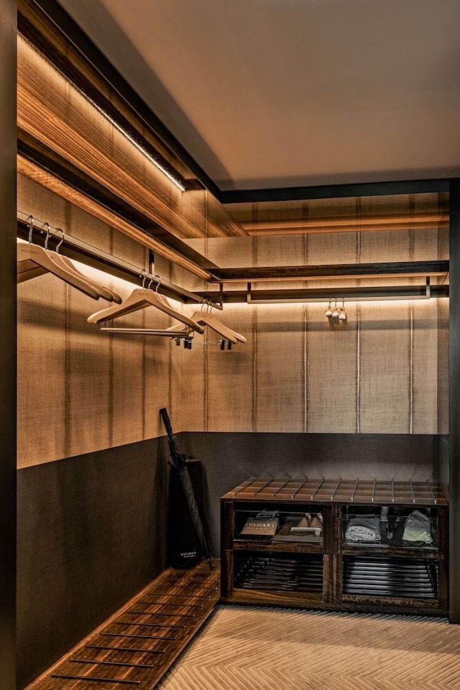 Warm LED strips illuminate handcrafted wooden hangers in this impeccably designed walk-in closet, where Italian craftsmanship meets functional luxury in every precisely placed detail.