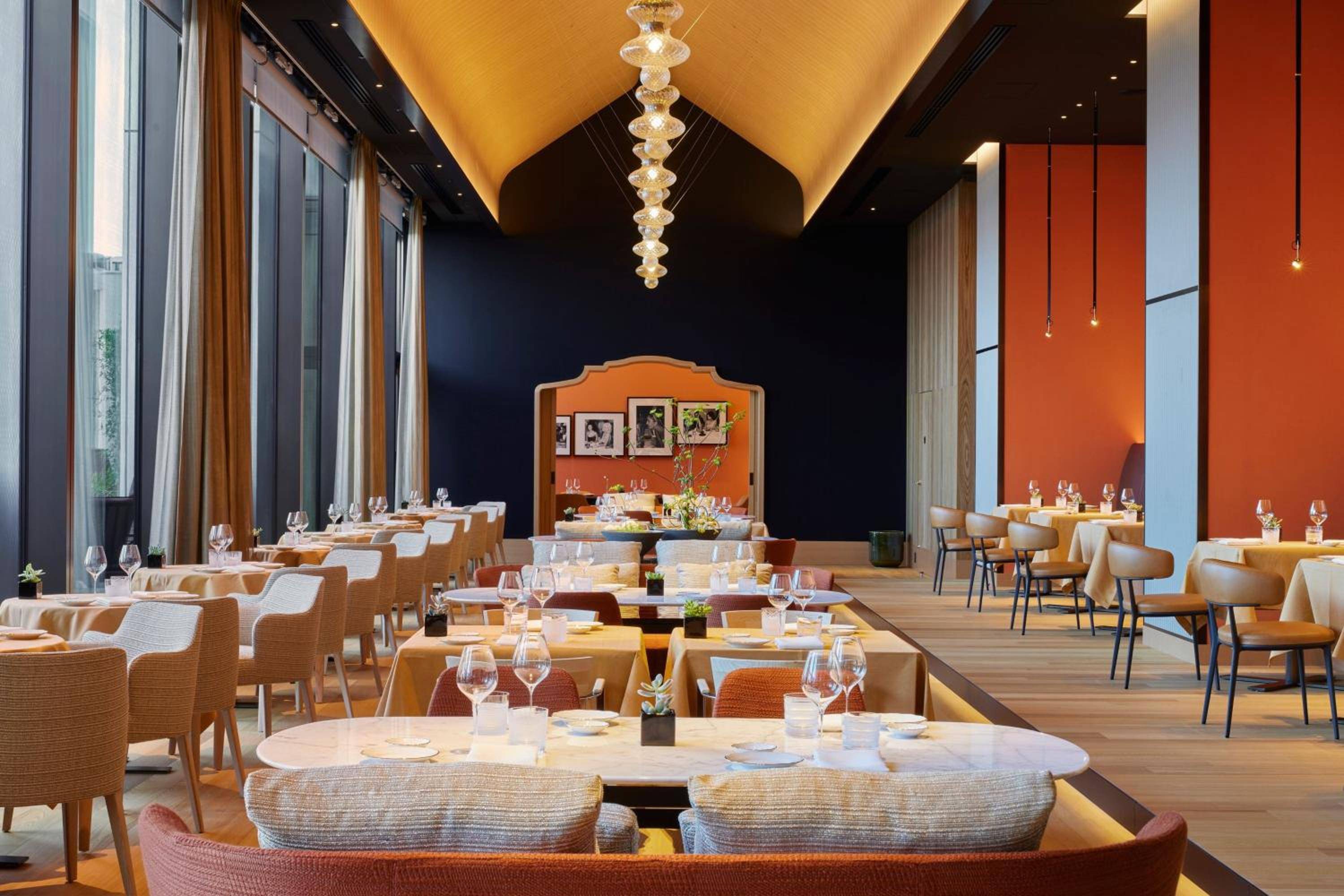 Warm amber lighting cascades over Il Ristorante's sophisticated dining room, where contemporary Italian elegance meets Tokyo's refined aesthetic through rich orange accents and crystalline chandeliers.