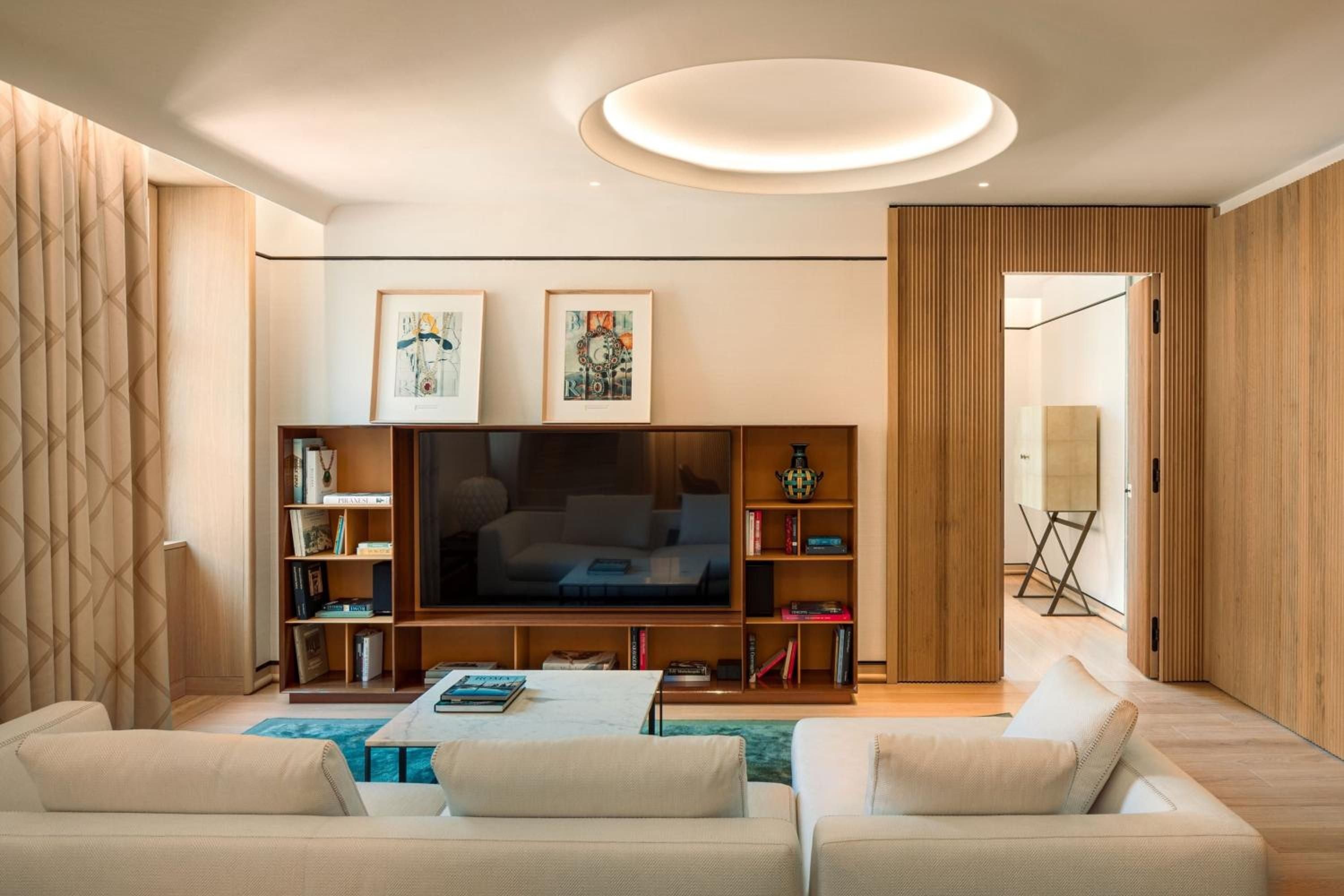 Warm timber shelving and sculptural ceiling details create an intimate living space where contemporary Italian design meets residential comfort in this sophisticated suite.