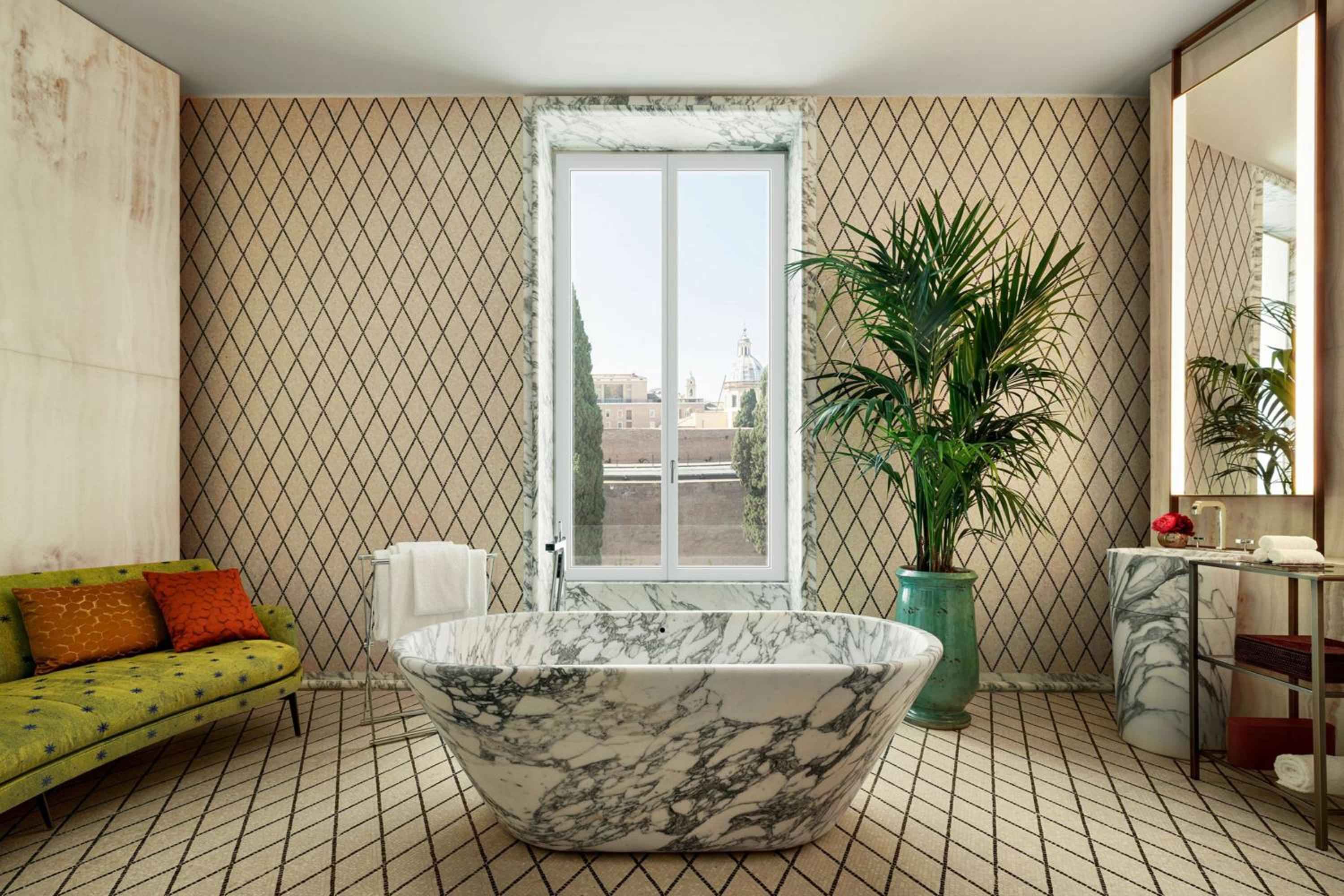 Geometric wallpaper and marble create striking contrasts in this sophisticated suite bathroom, where a sculptural tub overlooks Rome's ancient skyline through perfectly framed windows.