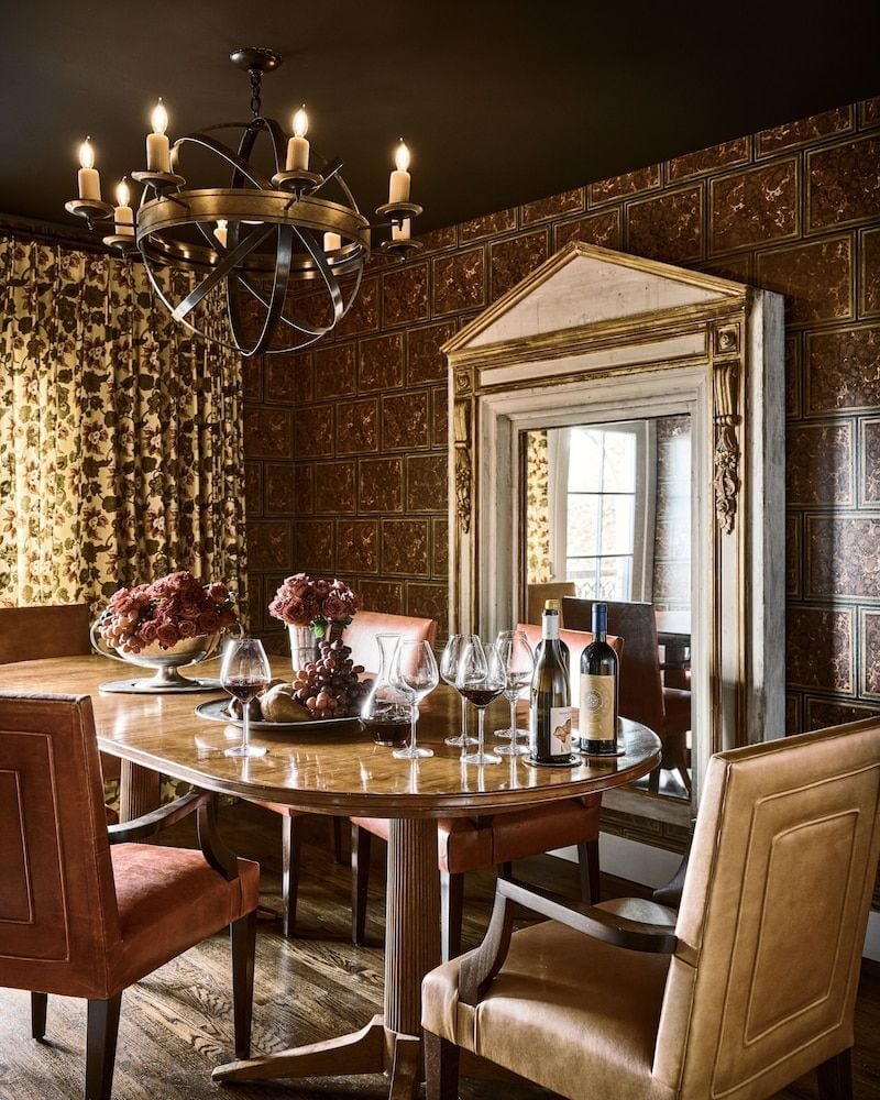 Ornate tin ceiling tiles and flickering candlelight create an intimate wine tasting corner, where leather chairs gather around polished wood for sophisticated evening tastings.