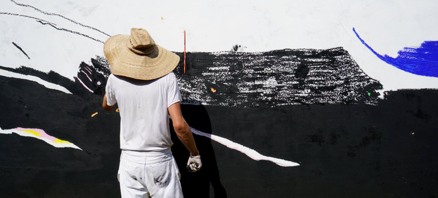 Street art comes alive as a local artist adds bold brushstrokes to Casa Wabi's vibrant exterior murals, blending creative expression with coastal Mexican culture.