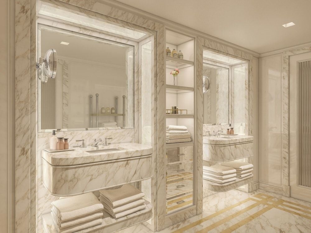 Calacatta marble envelops every surface in this opulent bathroom, where gleaming fixtures and warm lighting create an atmosphere of understated luxury.
