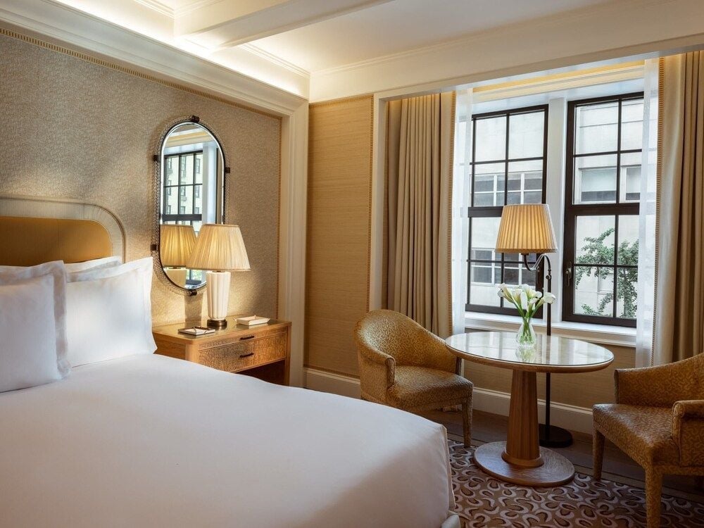 Warm amber light filters through tall windows, illuminating textured grasscloth walls and honey-toned furnishings that create an intimate sanctuary above Manhattan's bustling streets.