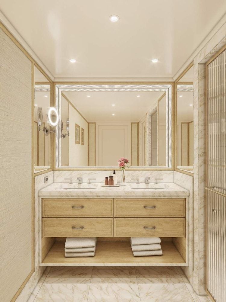 Warm wood vanities and pristine marble create a spa-like sanctuary, where dual sinks and thoughtful lighting transform daily rituals into moments of luxury.