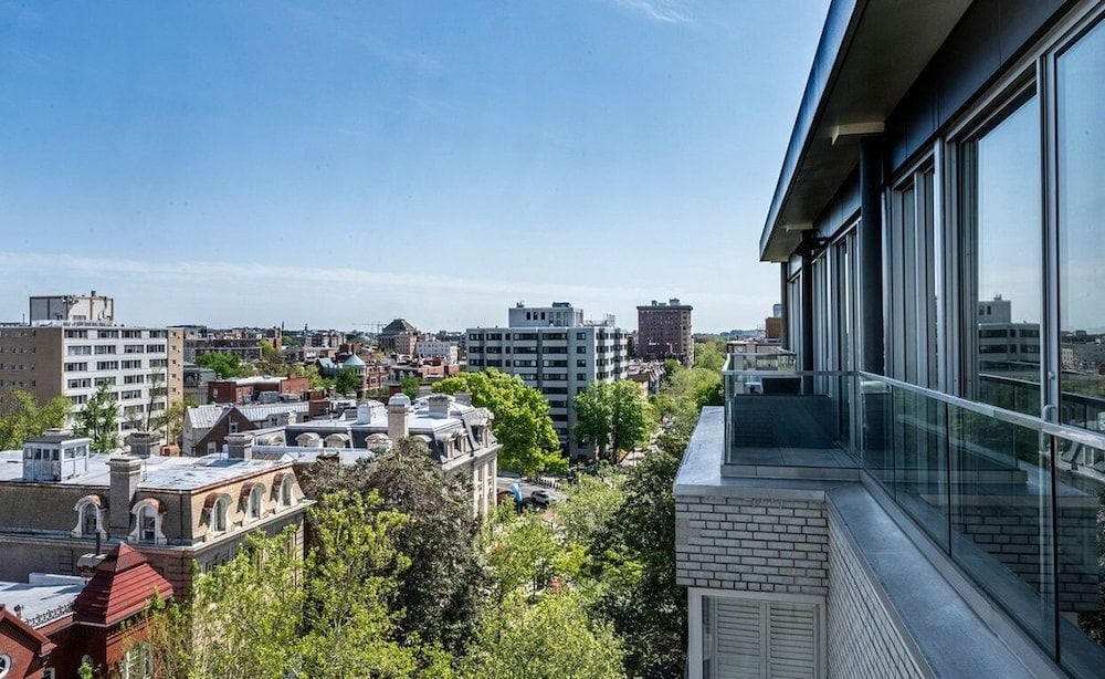 Floor-to-ceiling windows frame sweeping vistas of Dupont Circle's leafy streetscape from this elegant balcony, where urban sophistication meets neighborhood charm.
