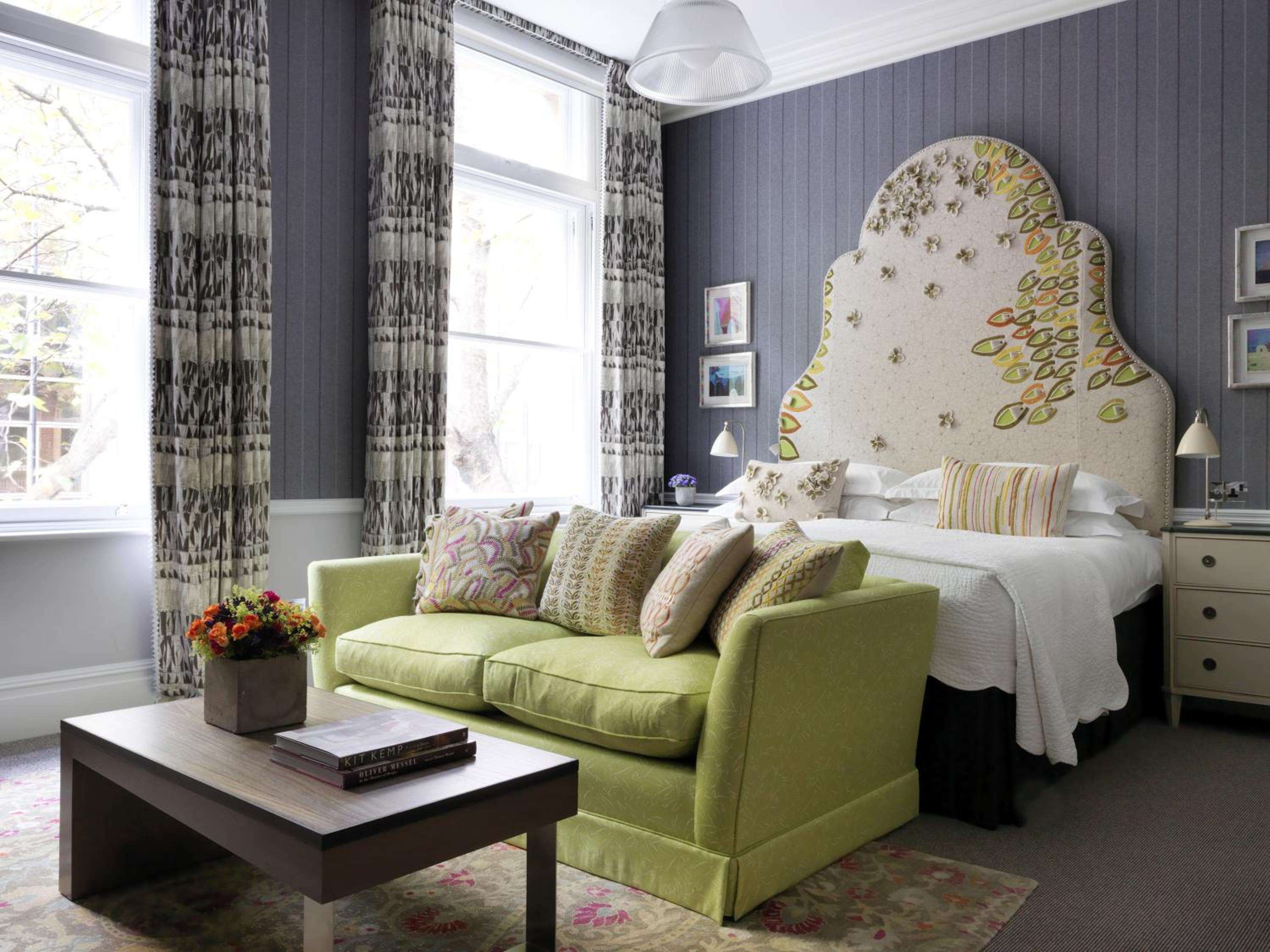 Lime-green velvet seating anchors this sophisticated guest room, where botanical headboard motifs and geometric curtains create London's most charming urban retreat.
