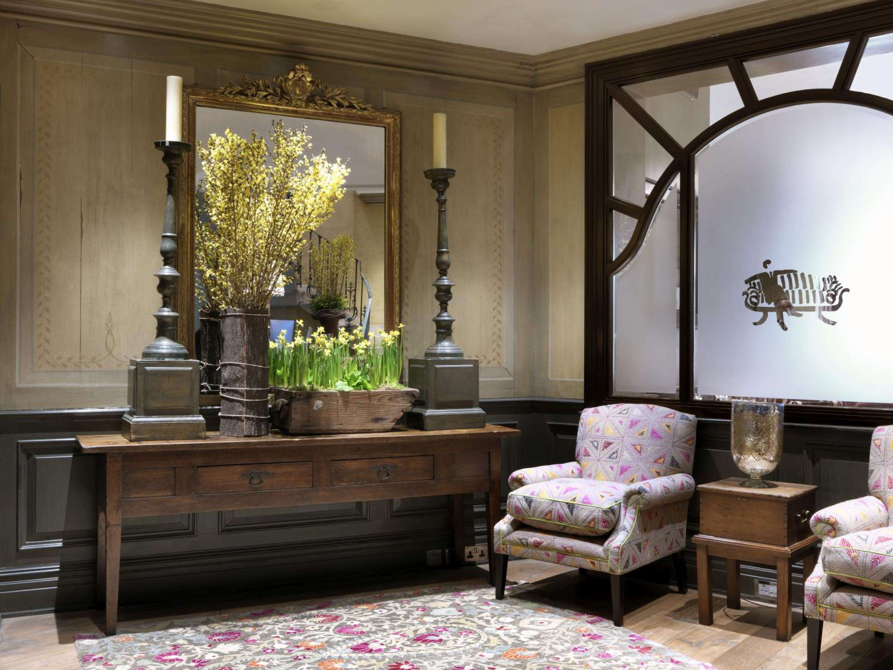 Burnished candlesticks and spring blooms create an elegant tableau in the wood-paneled lobby, where patterned armchairs invite lingering over afternoon tea.