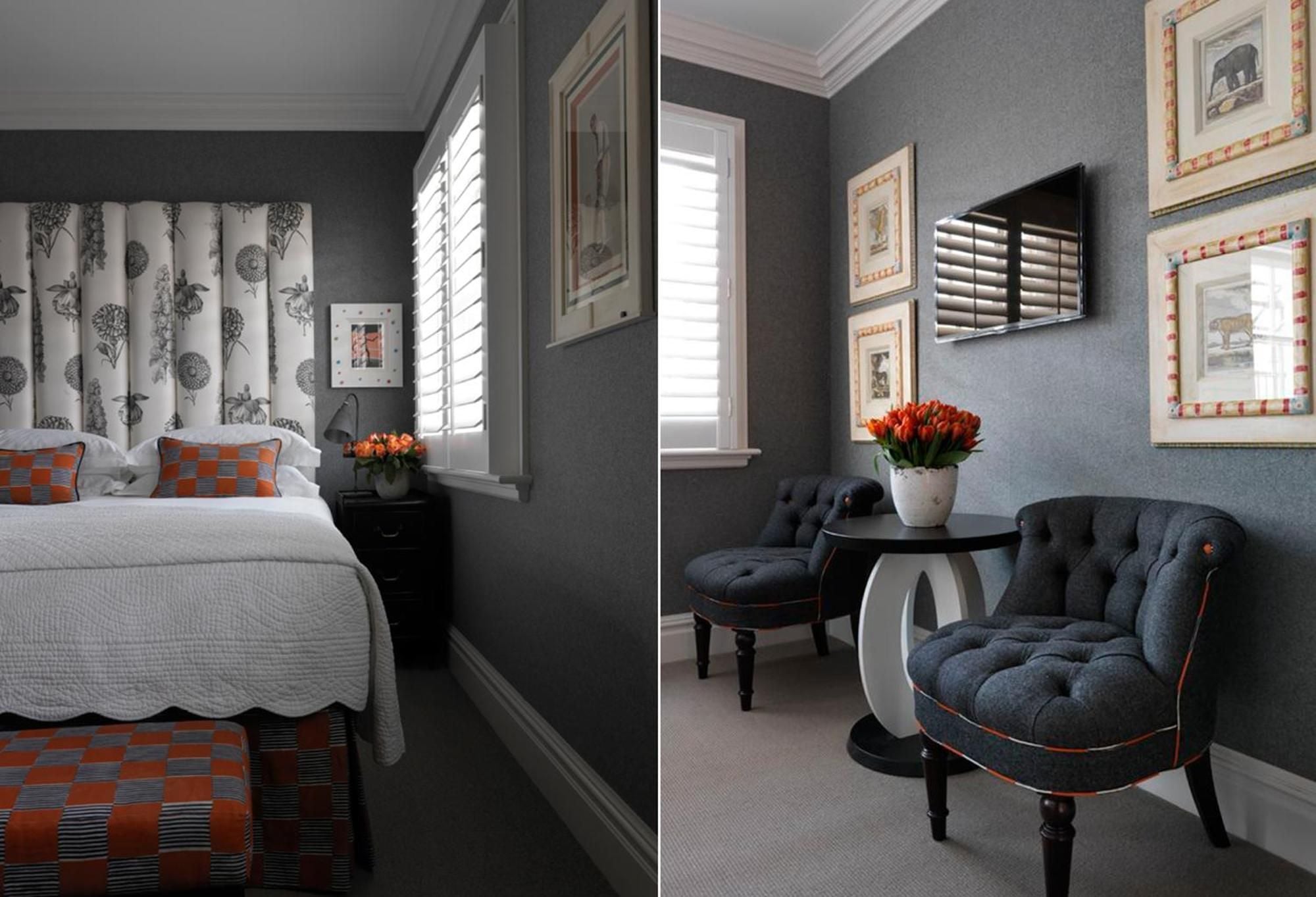 Charcoal walls create intimate drama in this thoughtfully appointed room, where botanical headboard prints and tufted navy chairs blend Georgian elegance with contemporary comfort.