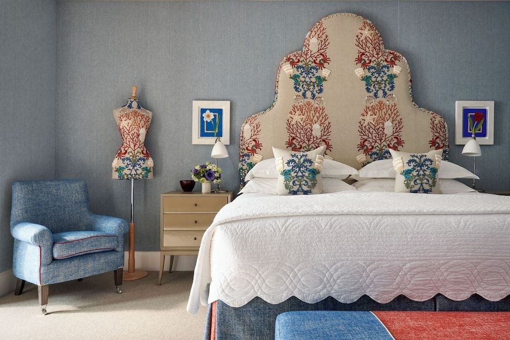 Botanical embroidered headboards and soft blue textures create an intimate sanctuary where English country charm meets contemporary London sophistication in every thoughtful detail.