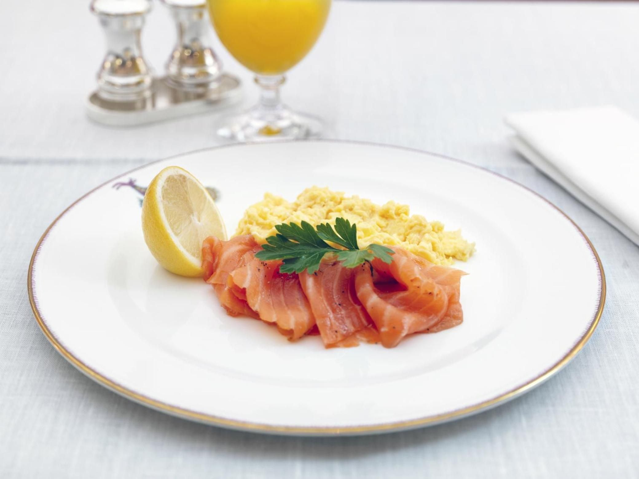 Delicate smoked salmon artfully arranged beside fluffy scrambled eggs, served on fine china with fresh parsley and lemon—breakfast elevated to an art form.