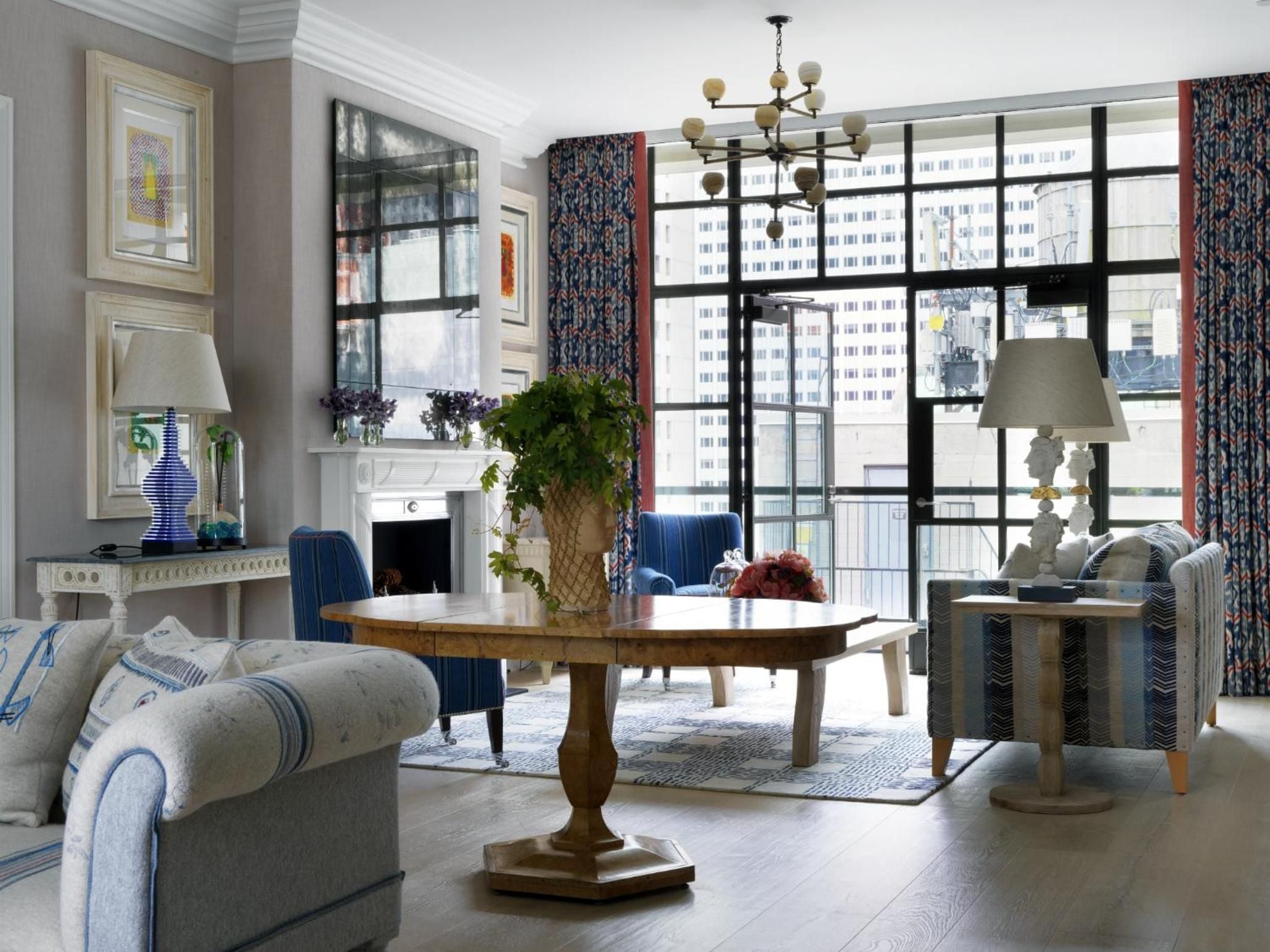 Light streams through steel-framed windows into this sophisticated suite, where navy accents and botanical prints create an urbane refuge above Manhattan's bustling streets.