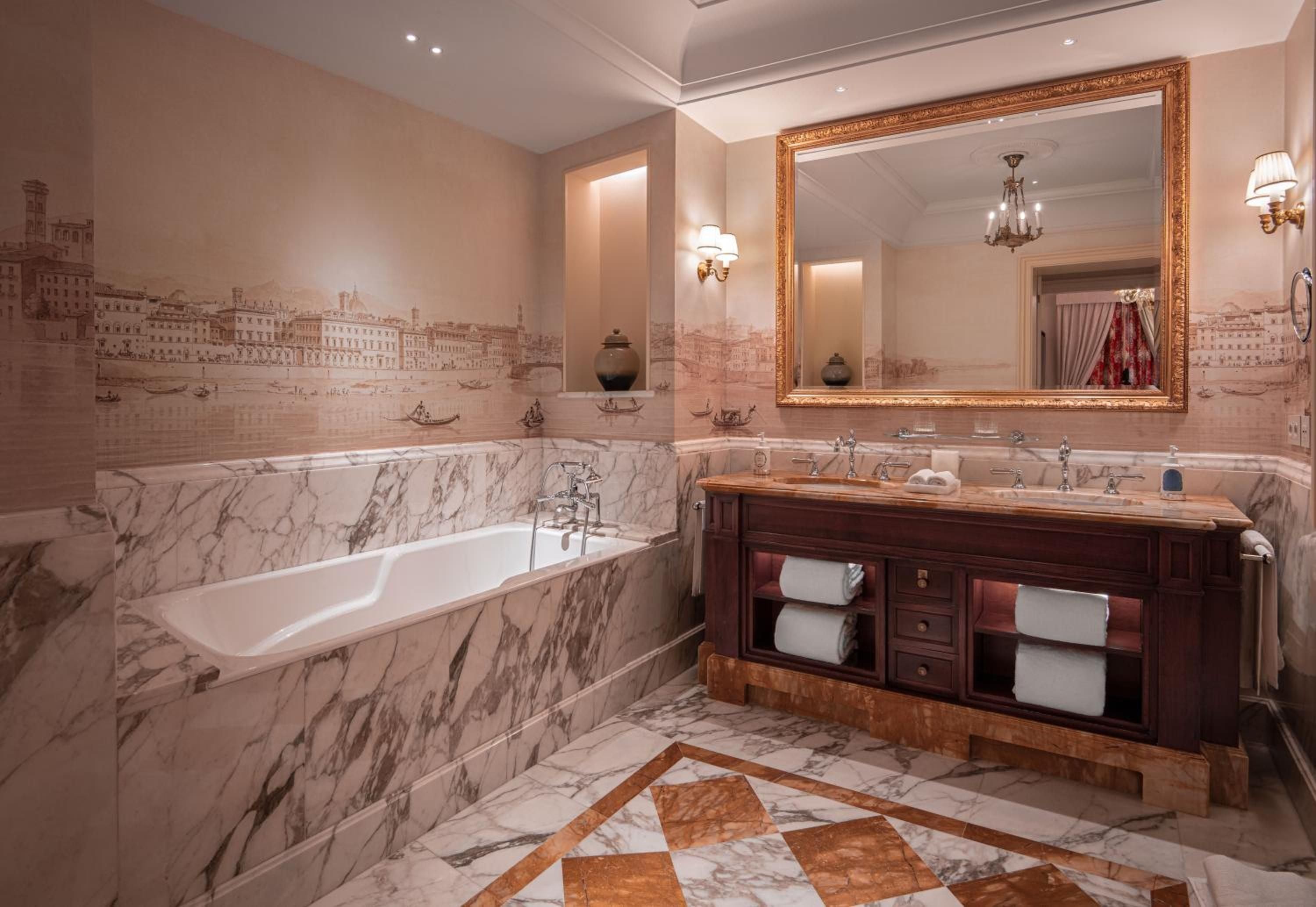 Venetian-inspired frescoes dance above Carrara marble in this opulent suite bathroom, where hand-painted cityscapes transform an evening soak into pure Renaissance romance.