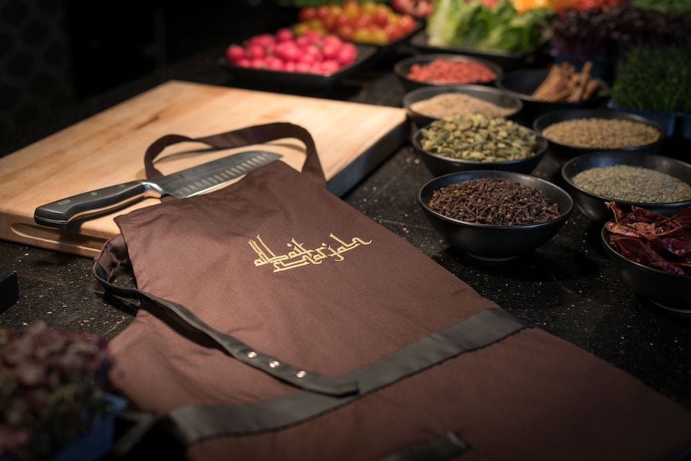 Aromatic spices cascade from dark bowls while a leather-bound apron awaits the next culinary demonstration, transforming dining into an immersive cultural journey.