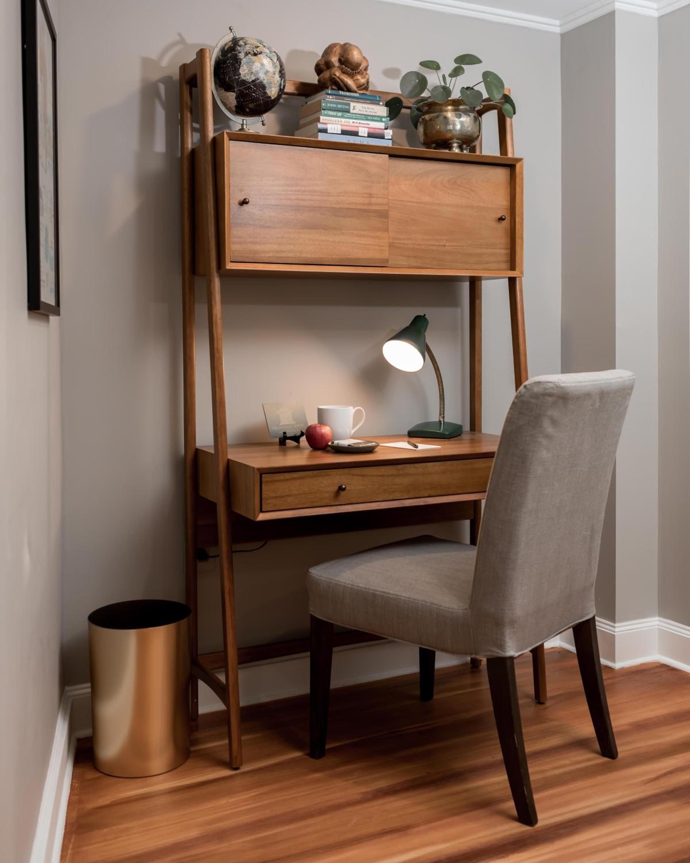 Warm walnut wood and brass accents create an intimate workspace where vintage globes and carefully curated books invite quiet contemplation beneath soft task lighting.