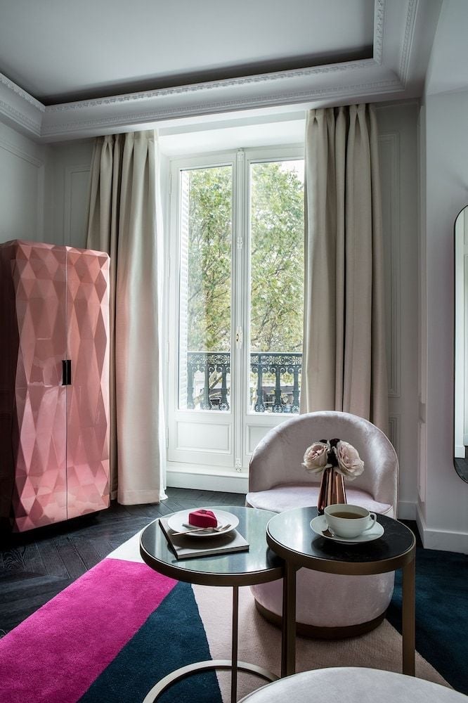 Coral-pink textured cabinetry adds playful sophistication to this Parisian suite, where geometric patterns meet classic Haussmann architecture through floor-to-ceiling French doors.