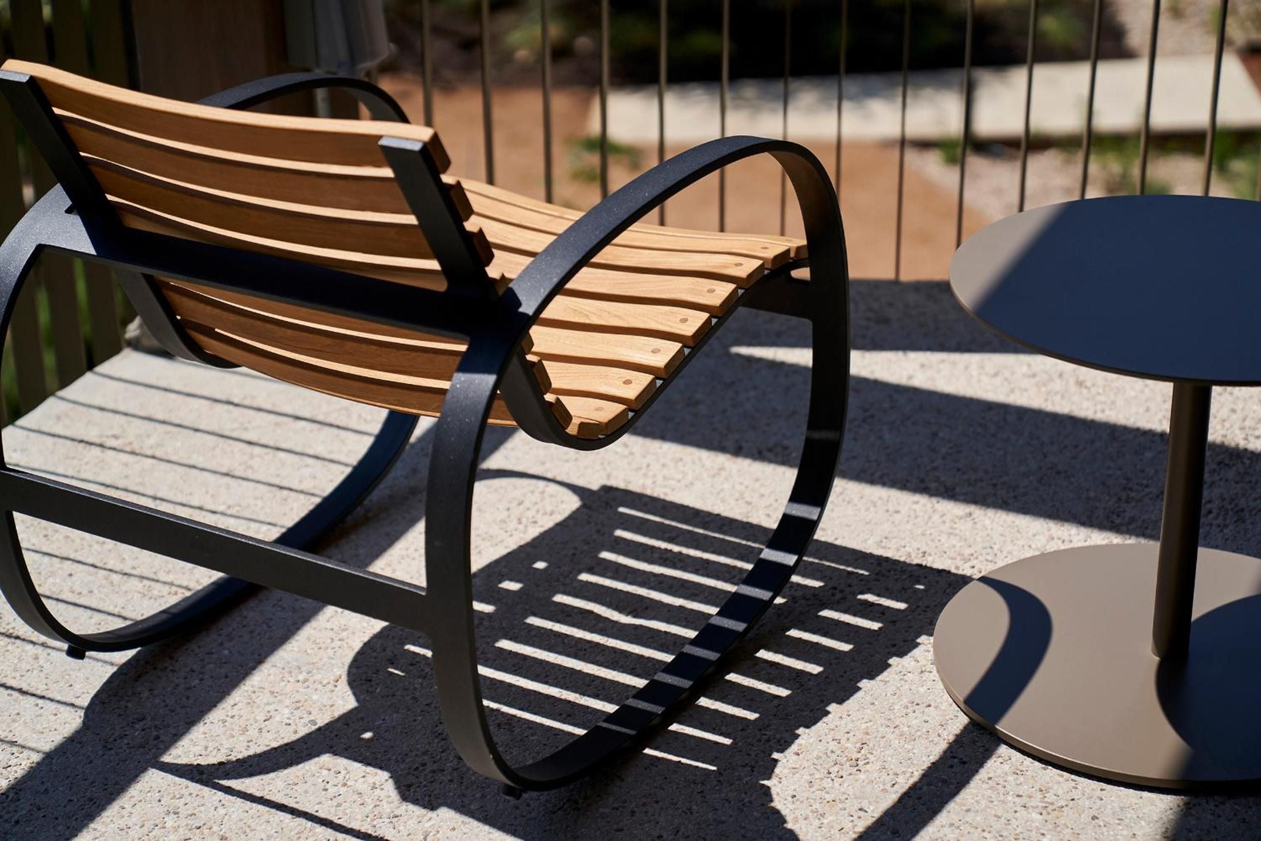 Curved wooden slats and dark metal frames create striking shadows on sun-warmed concrete, where modern design meets Austin's laid-back outdoor living culture.