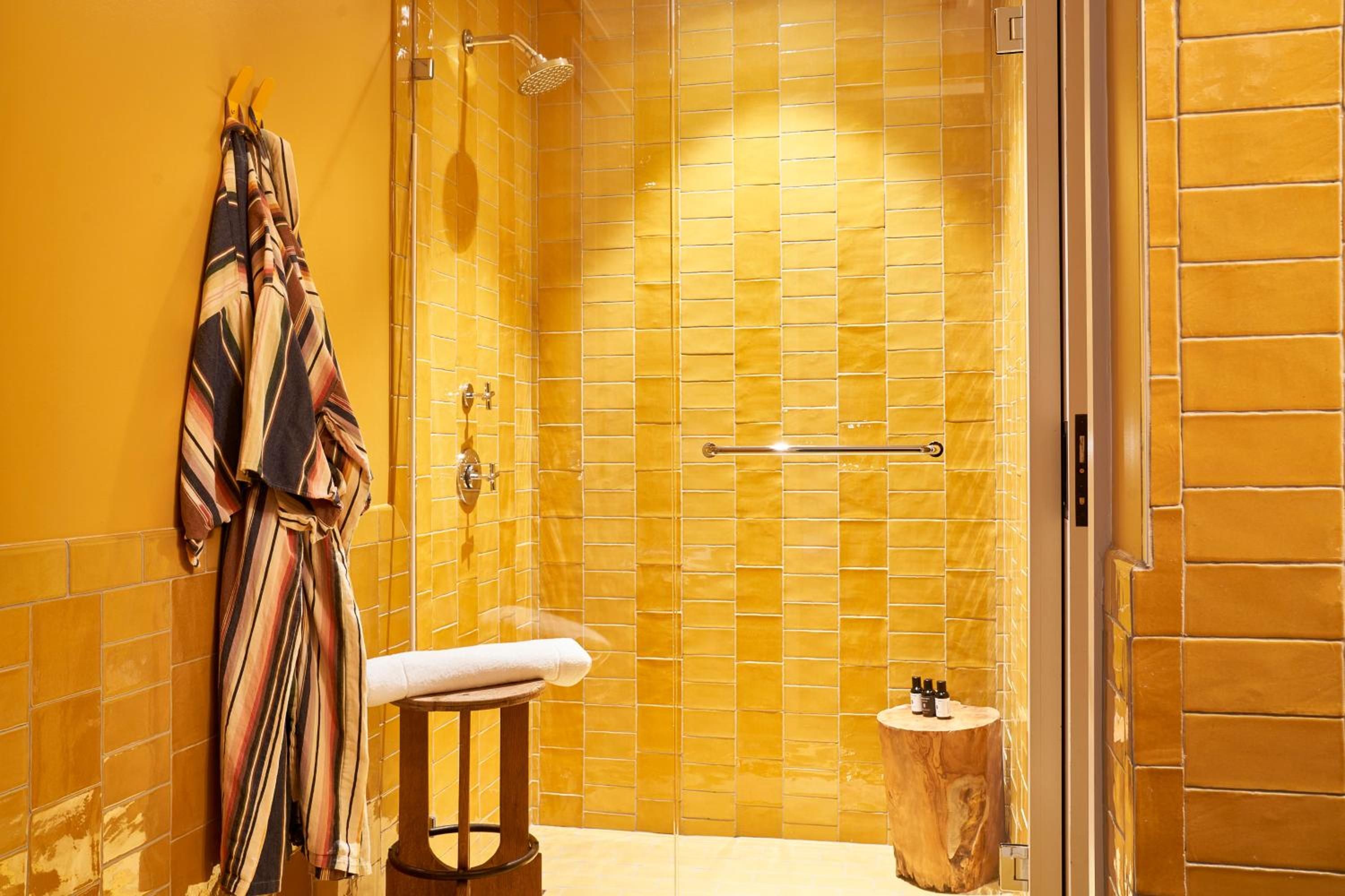 Golden zellige tiles create a honey-hued sanctuary where warm light dances across handcrafted surfaces, transforming the walk-in shower into a luminous retreat.
