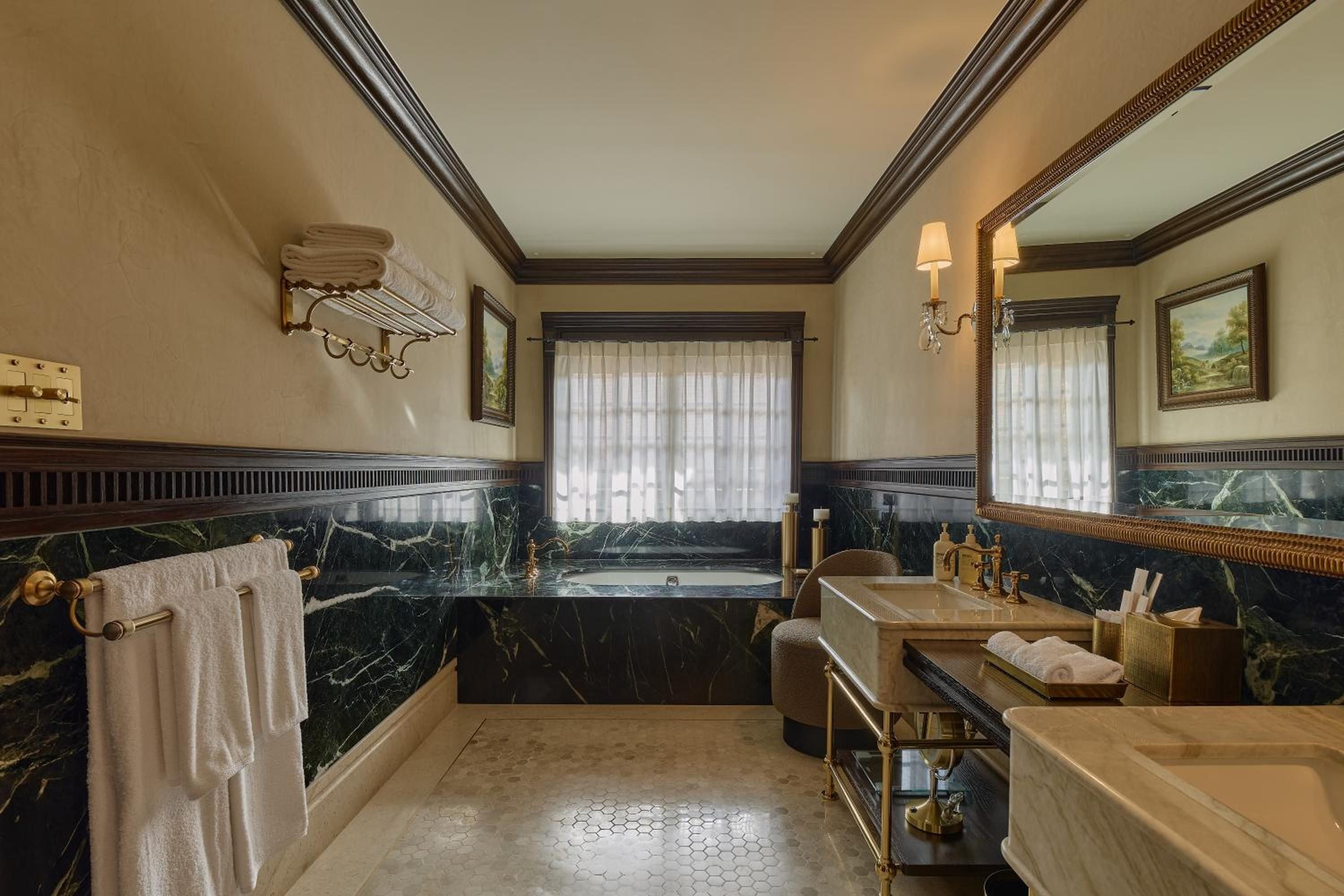 Emerald marble walls and coffered ceilings create an opulent sanctuary where brass fixtures gleam against hexagonal mosaic floors in this palatial bathroom retreat.