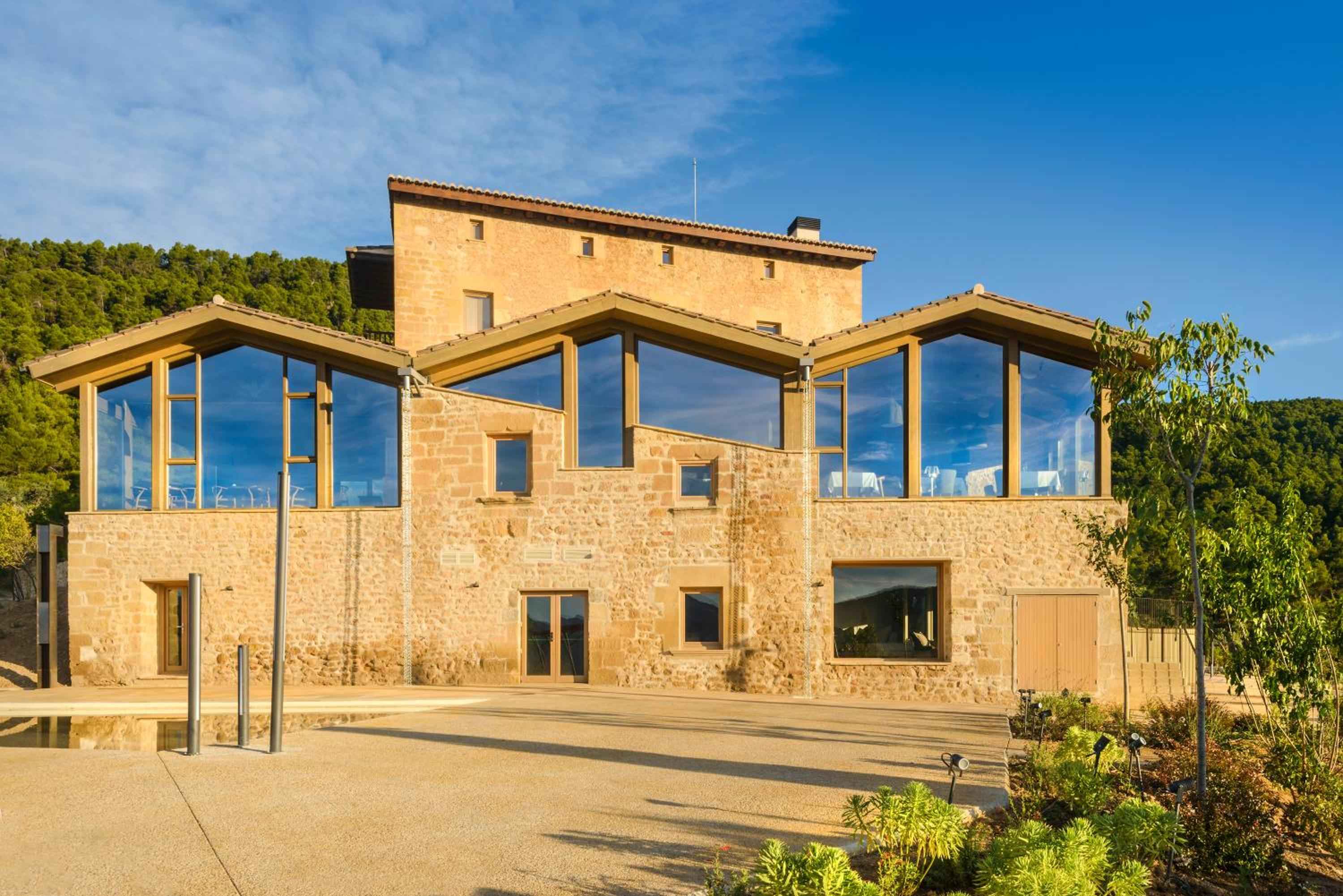Golden limestone walls catch Mediterranean light as contemporary glass pavilions extend from the historic tower, creating striking dialogue between old and new architecture.