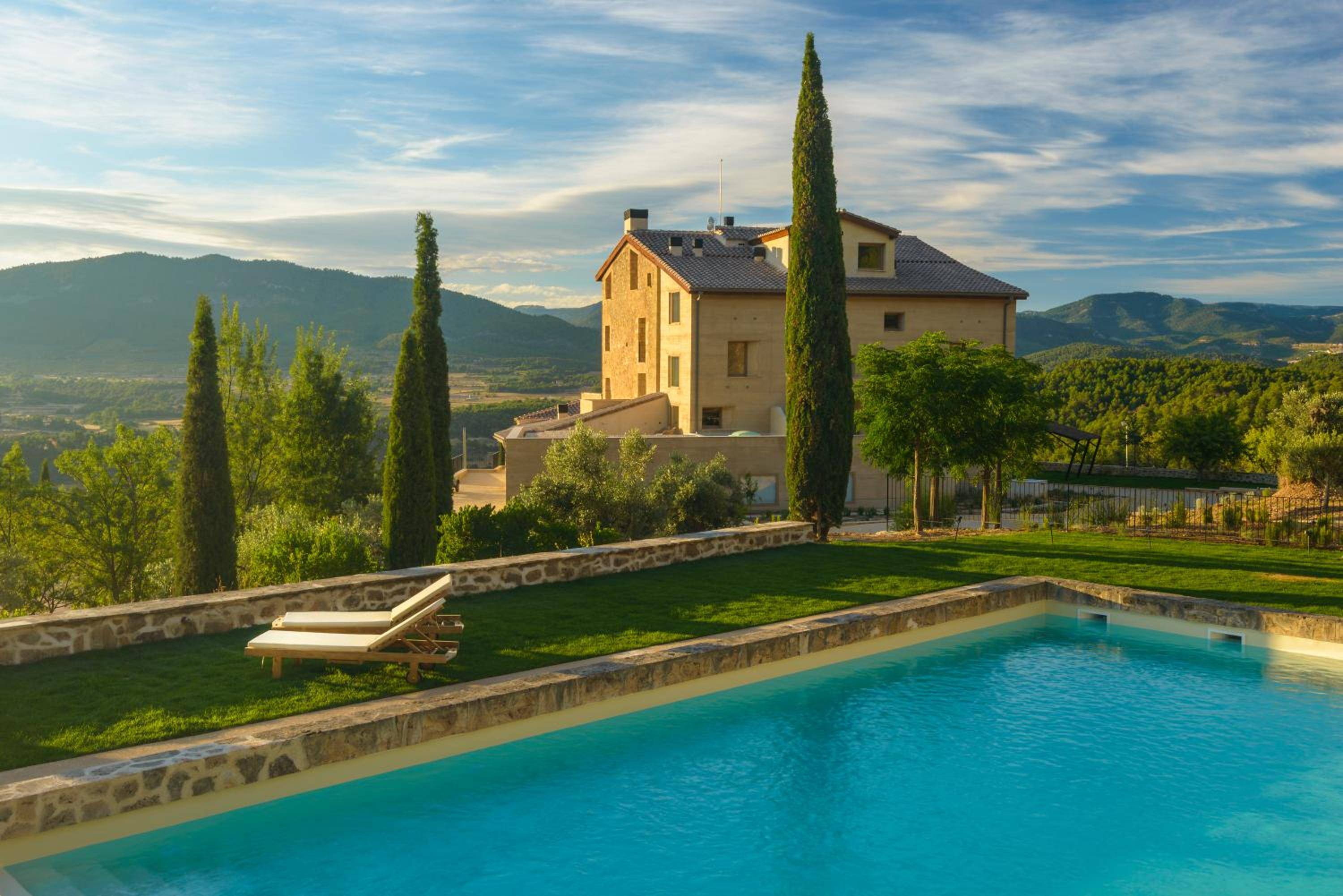 Golden hour light bathes the infinity pool while towering cypress trees frame panoramic valley views from this elevated Tuscan sanctuary.