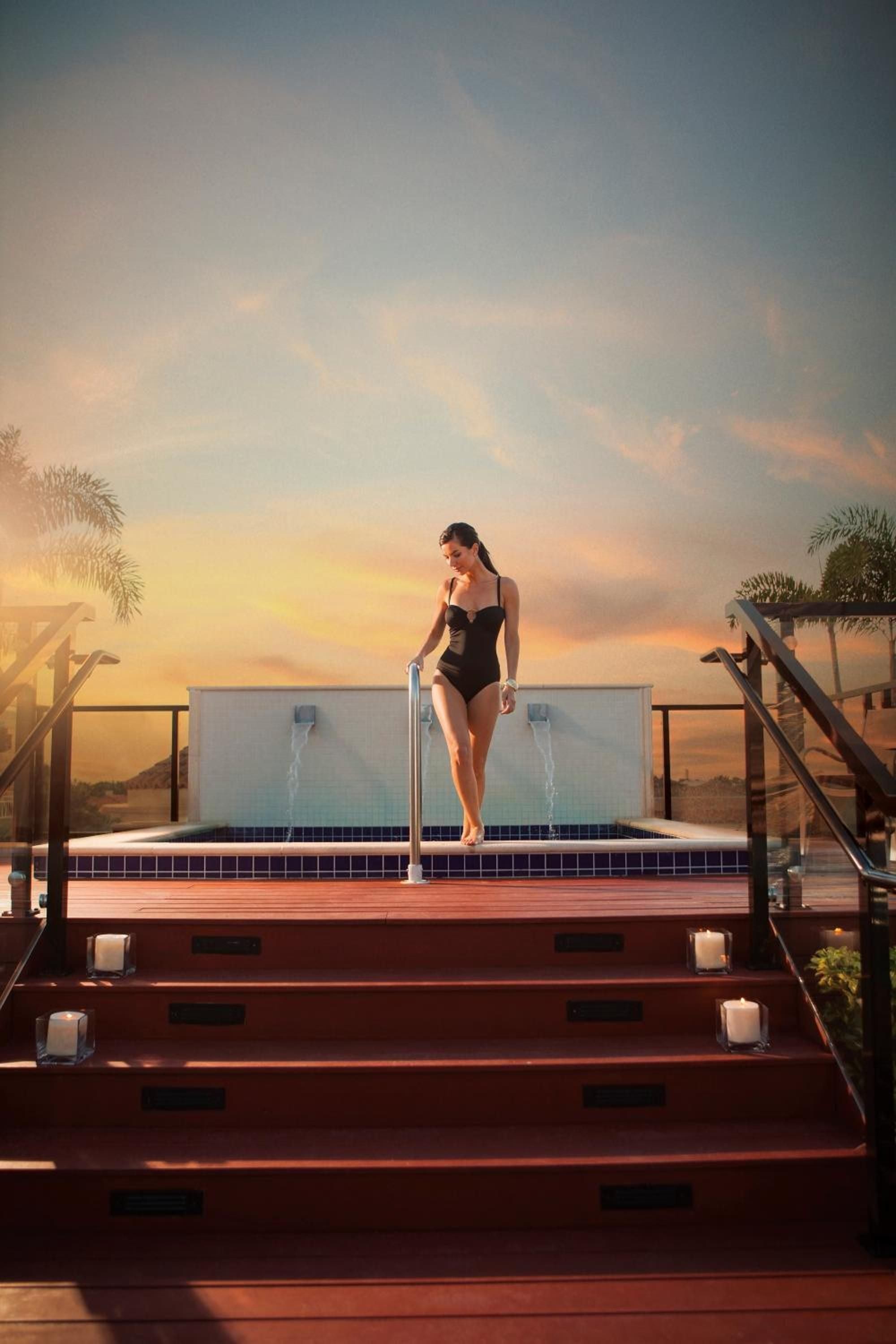 Golden hour transforms the rooftop infinity pool into a private sanctuary, where warm waters meet endless sky above Naples' sophisticated skyline.