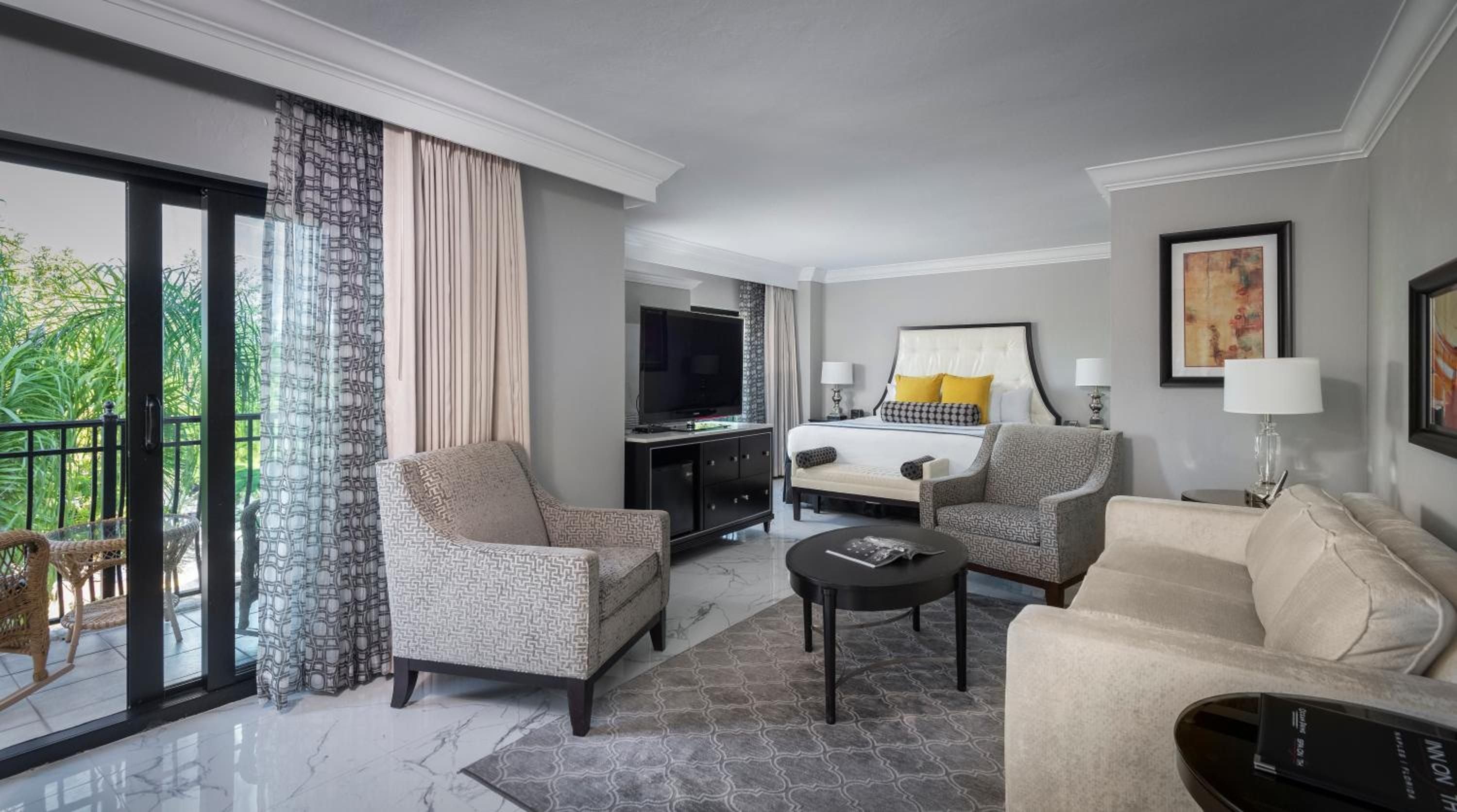 Sophisticated neutrals and marble floors create an elegant retreat where floor-to-ceiling windows frame tropical views and thoughtful seating arrangements invite lingering conversations.