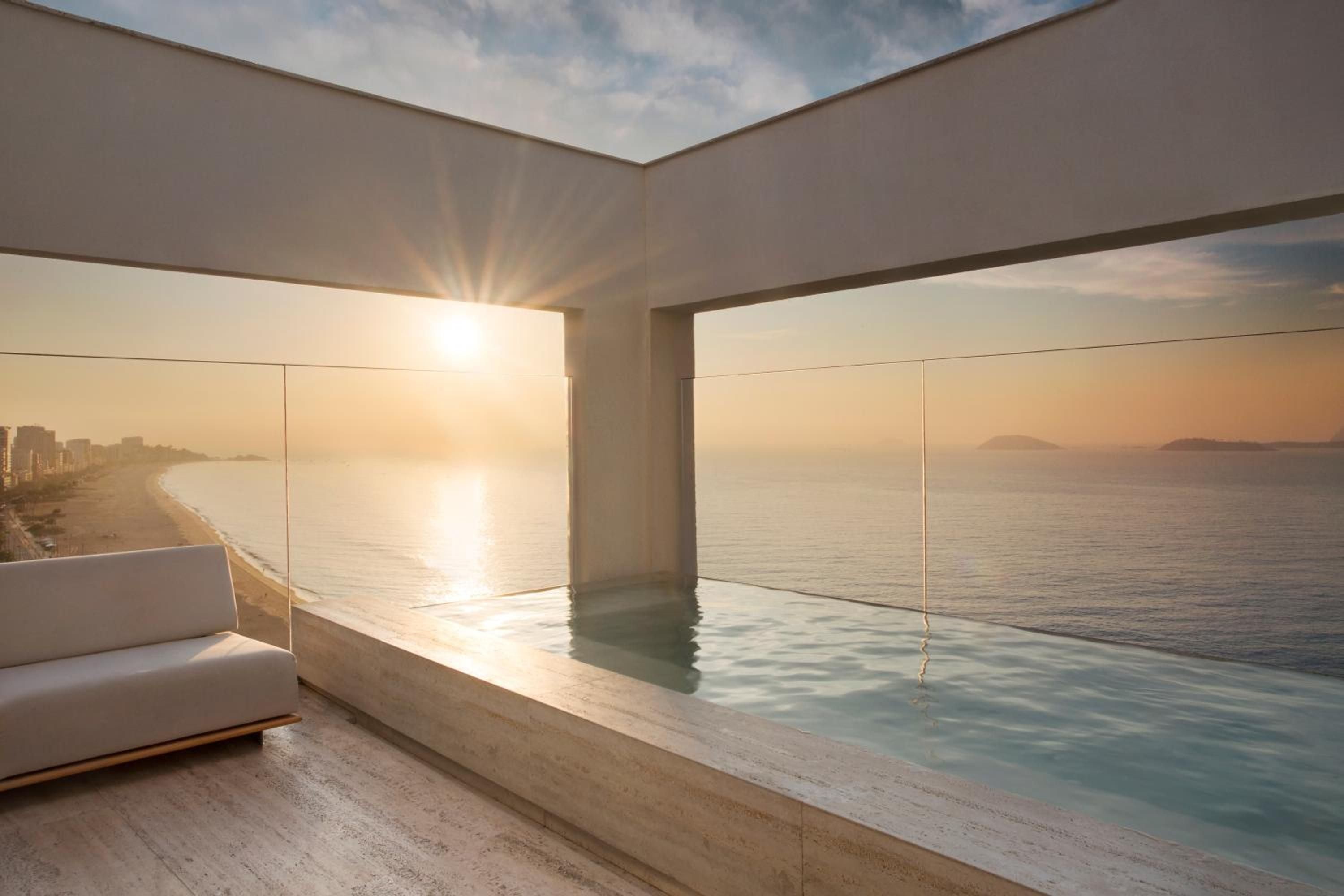 Infinity waters blur the line between pool and ocean as golden hour light streams through floor-to-ceiling glass, creating an ethereal sanctuary above the coastline.