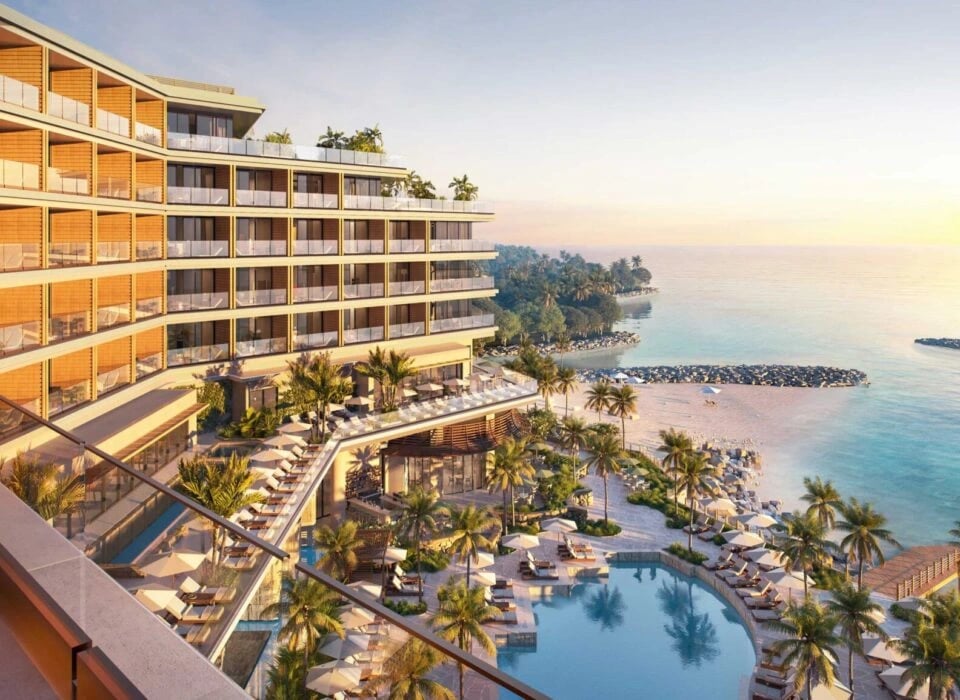 Golden hour bathes the resort's terraced architecture while guests drift between the infinity pool and pristine sand, palm fronds swaying in the tropical breeze.