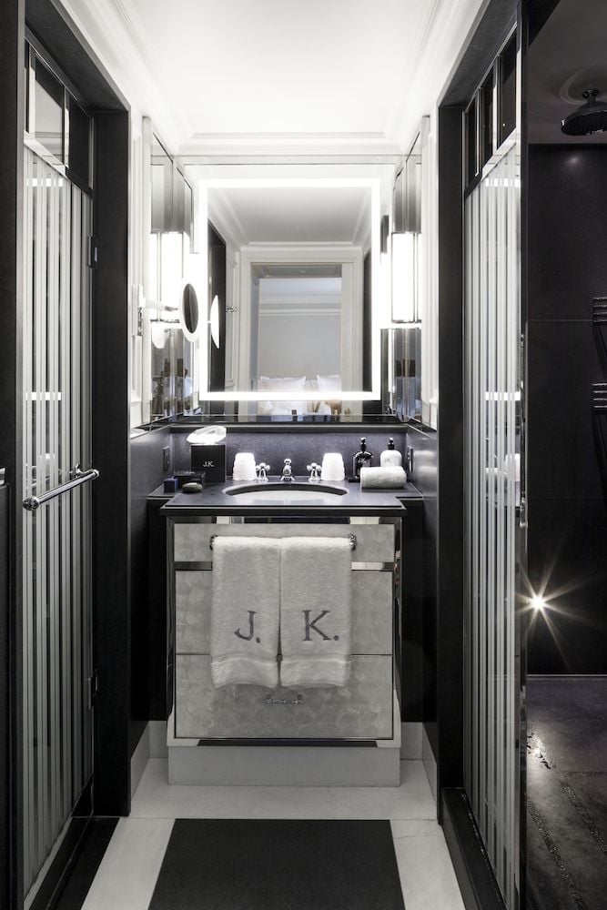 Monogrammed towels and gleaming fixtures transform the intimate bathroom into a jewel box of refined luxury, where black marble meets crisp white linens.