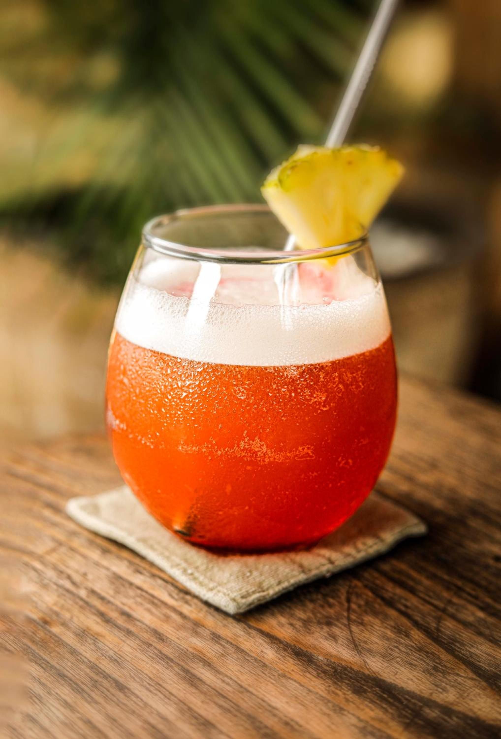 Sunset hues swirl through a tropical cocktail adorned with fresh pineapple, each sip capturing the golden hour magic that defines evenings at this Balinese retreat.