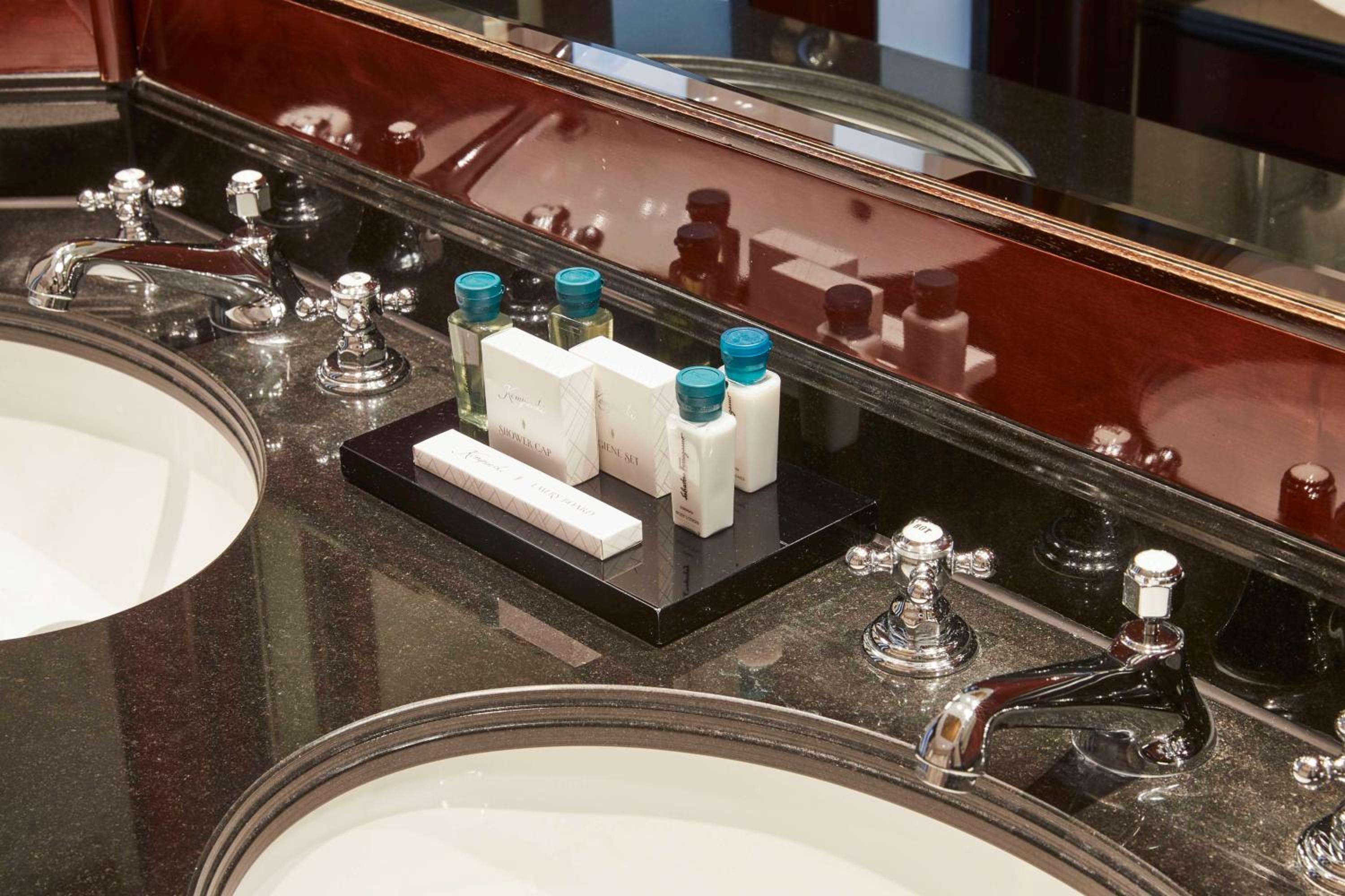 Polished granite countertops reflect chrome fixtures and curated amenities, where thoughtful touches like artisanal soaps transform daily rituals into moments of quiet luxury.