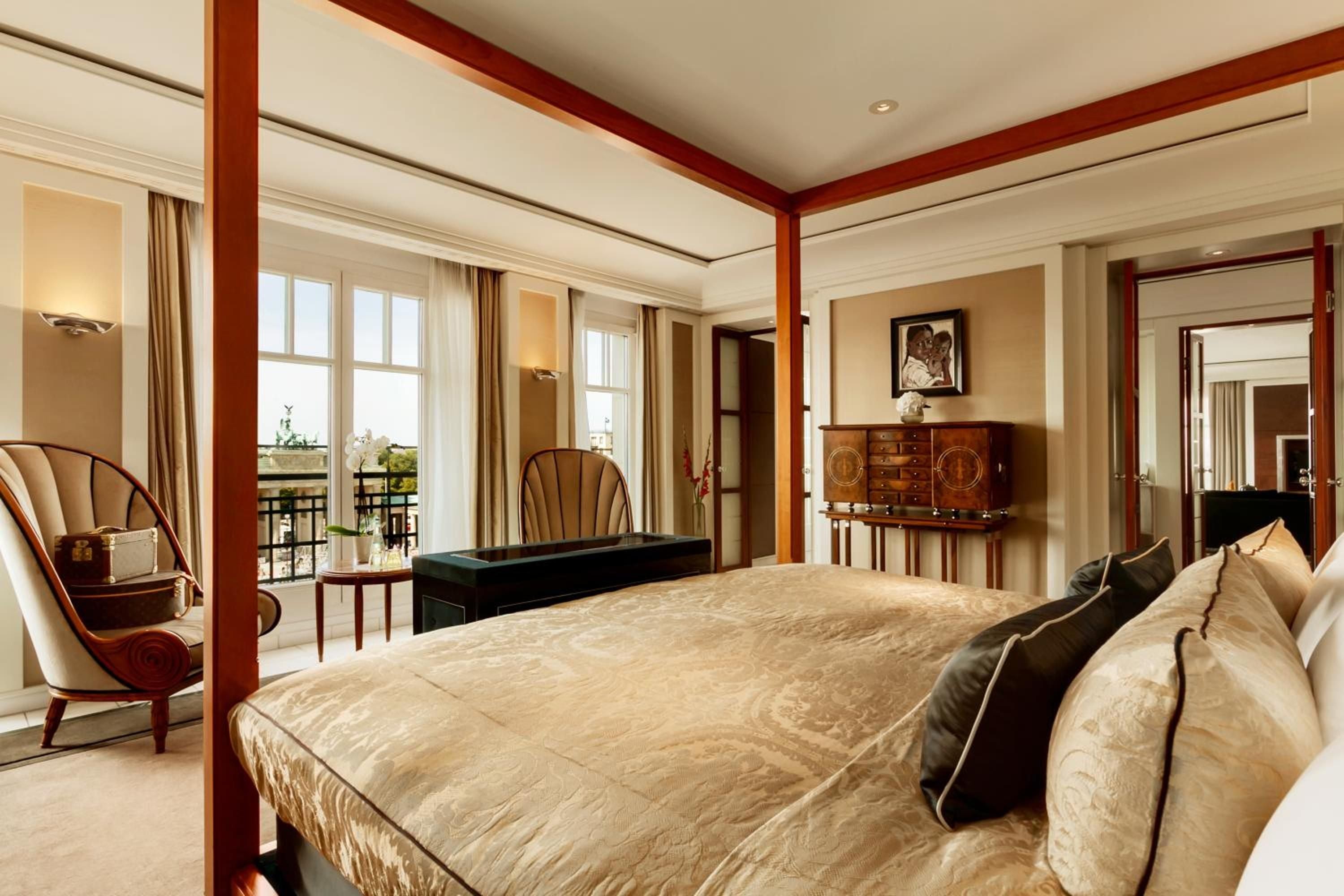 Rich mahogany four-poster frames sumptuous gold linens while Brandenburg Gate views unfold beyond silk curtains in this opulent suite overlooking Berlin's historic heart.