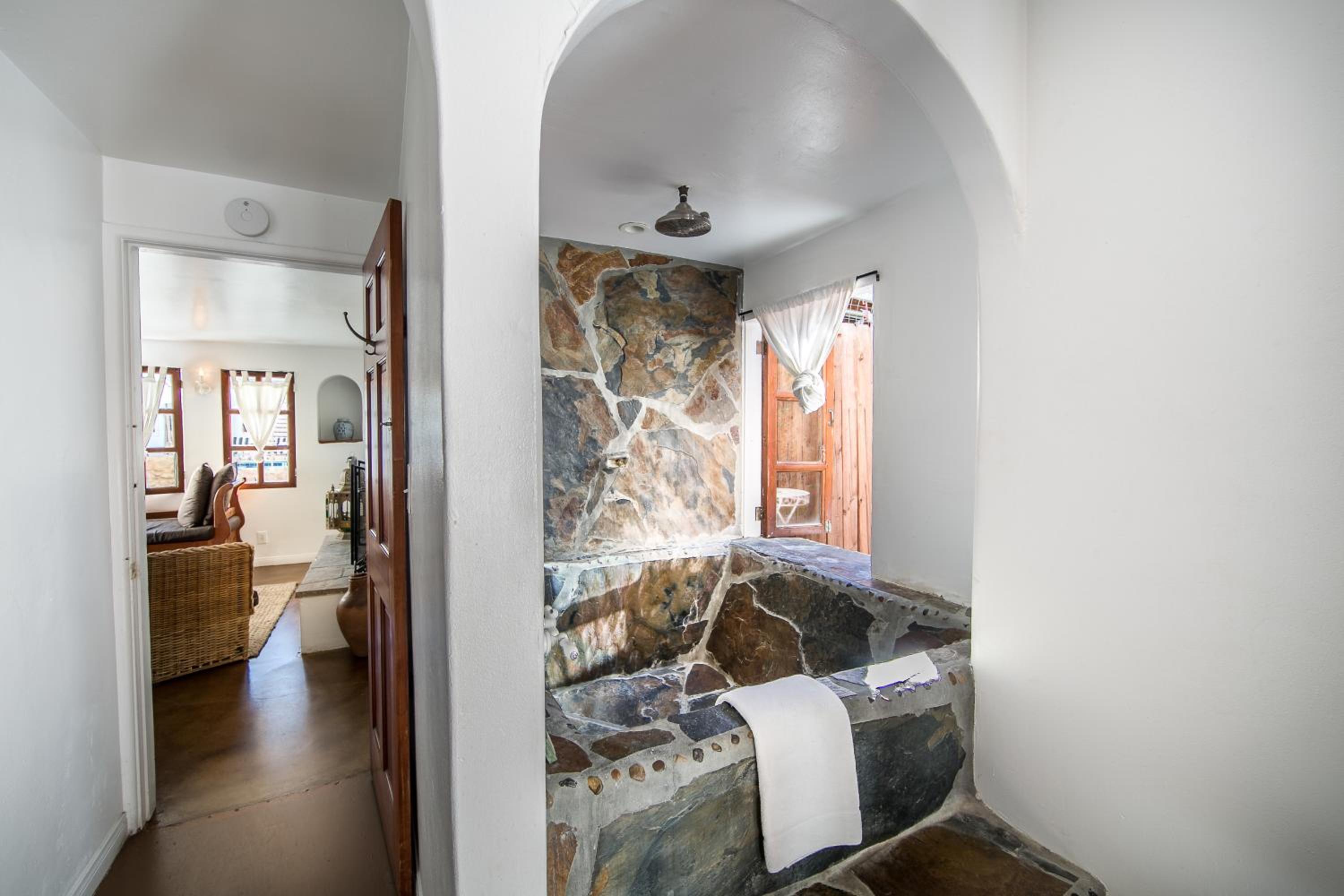 Natural stone transforms this intimate bathing alcove into a grotto-like sanctuary, where rough-hewn walls and arched ceilings create an almost cave-like serenity.